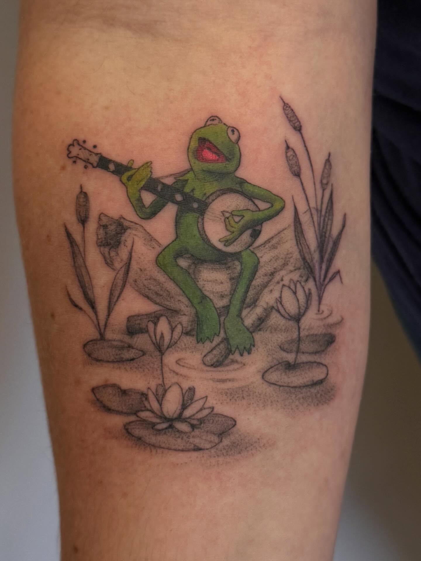 Kermit the frog playing banjo realism tattoo on the forearm by Peter Harren