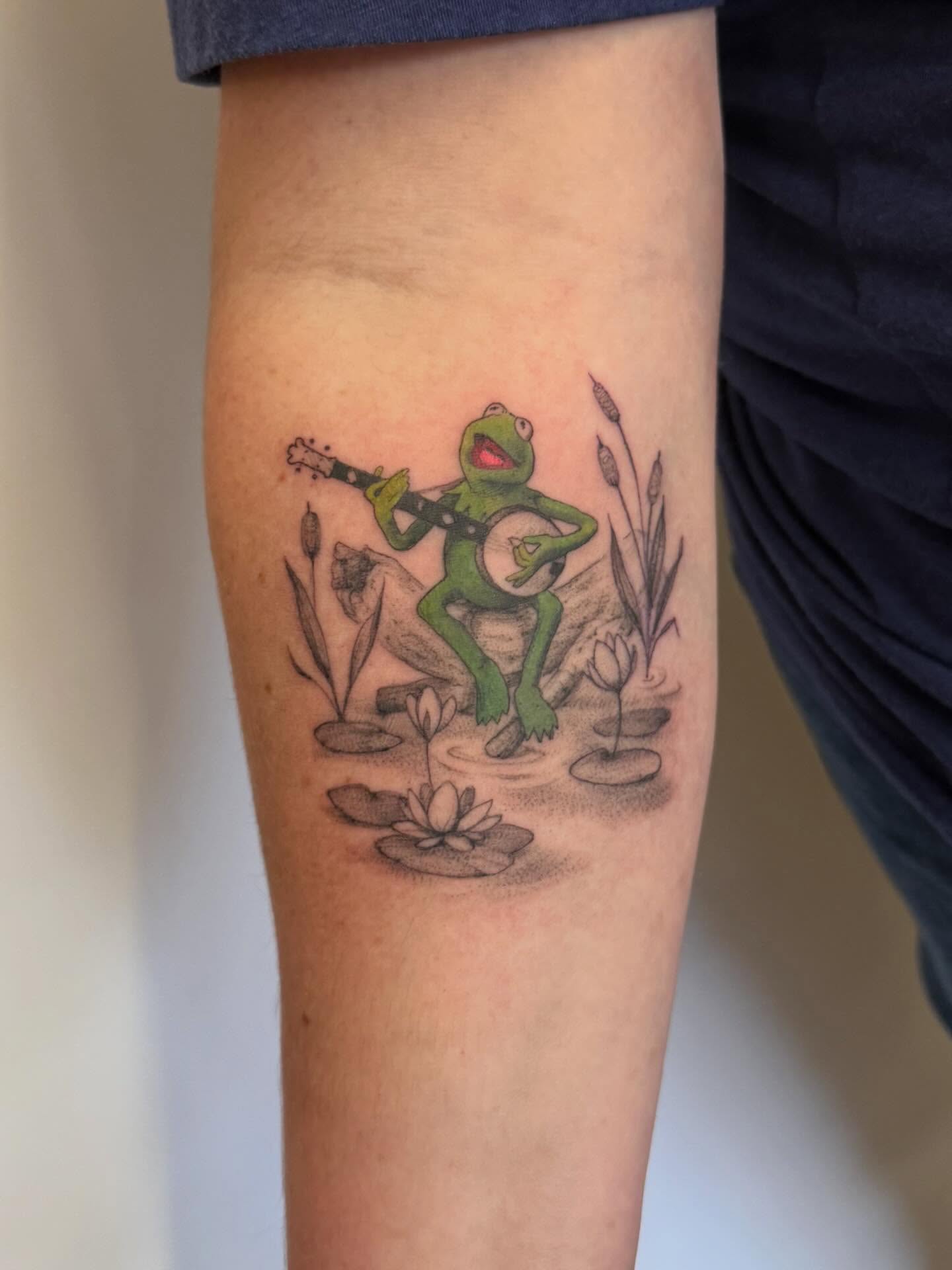 Kermit the frog playing banjo realism tattoo on the forearm by Peter Harren
