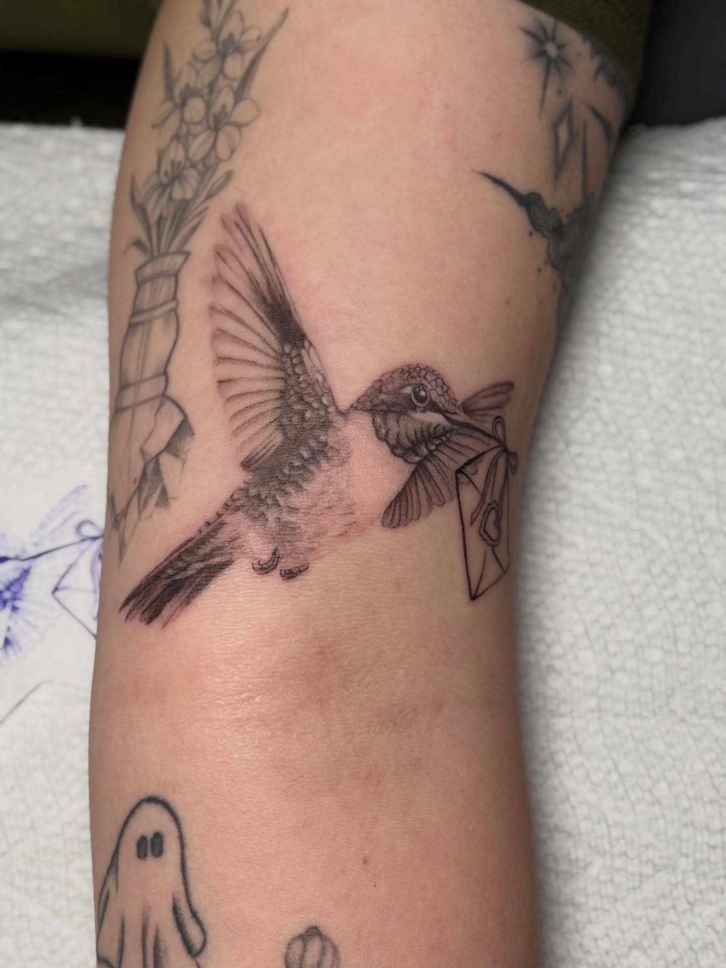 Hummingbird with envelope realism tattoo on the forearm by jaz🌀
