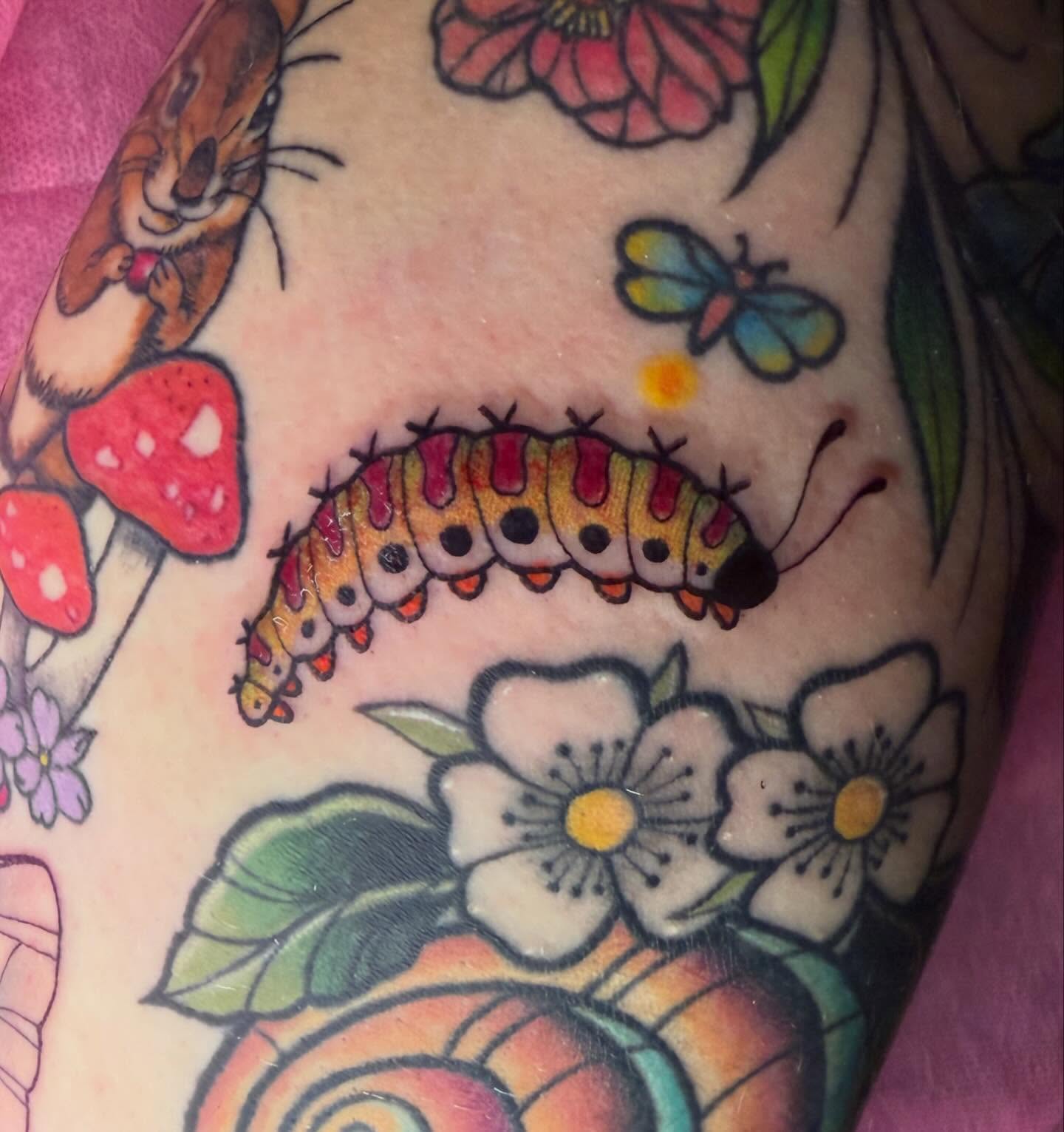Caterpillar and flowers American traditional tattoo on the upper arm by Olivia Whan Tattoos🌙