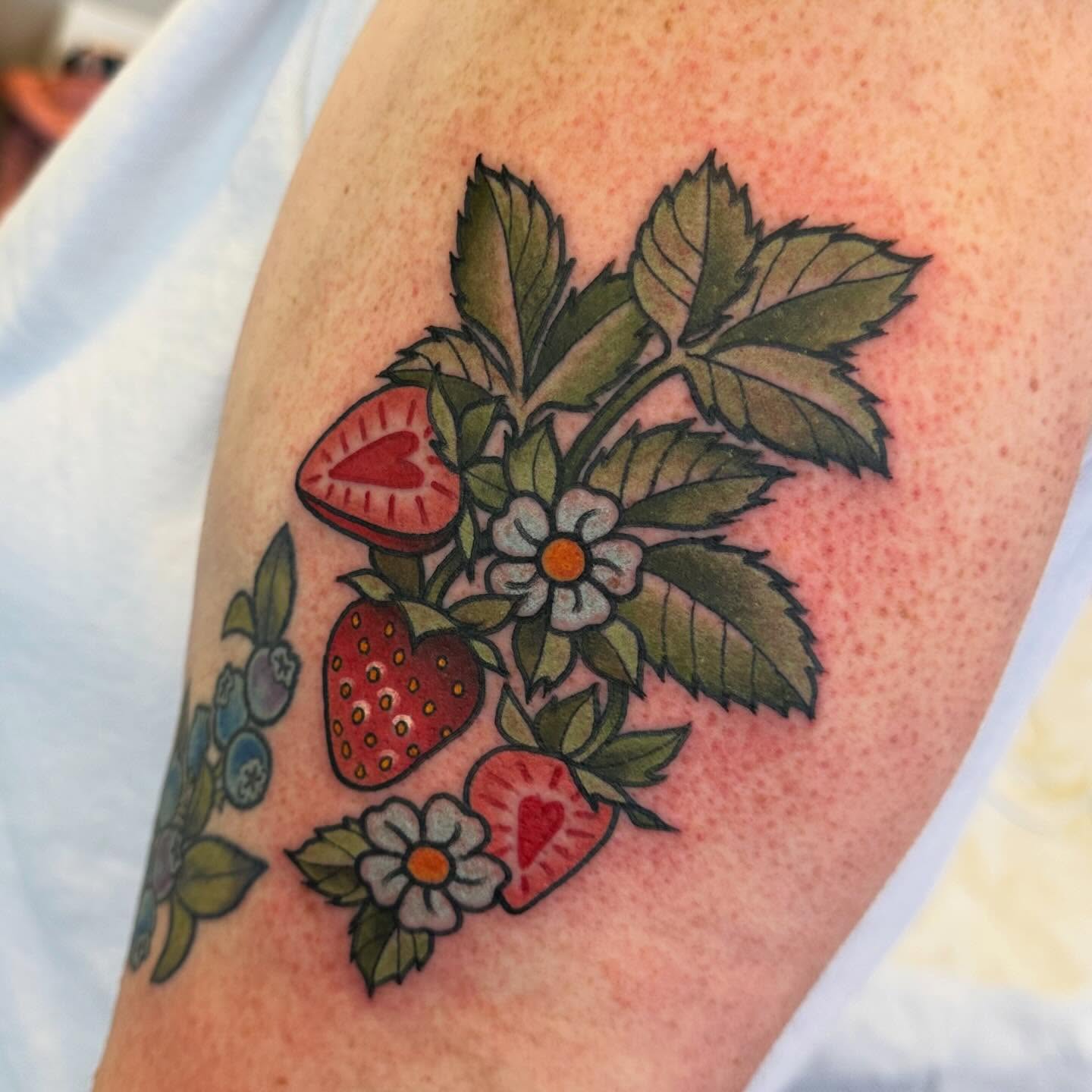 Strawberries and flowers American traditional tattoo on the forearm by Katie Beth