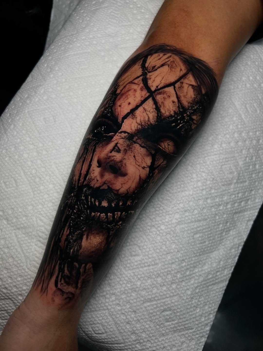 Creepy doll face dark art tattoo on the forearm by James Foltz