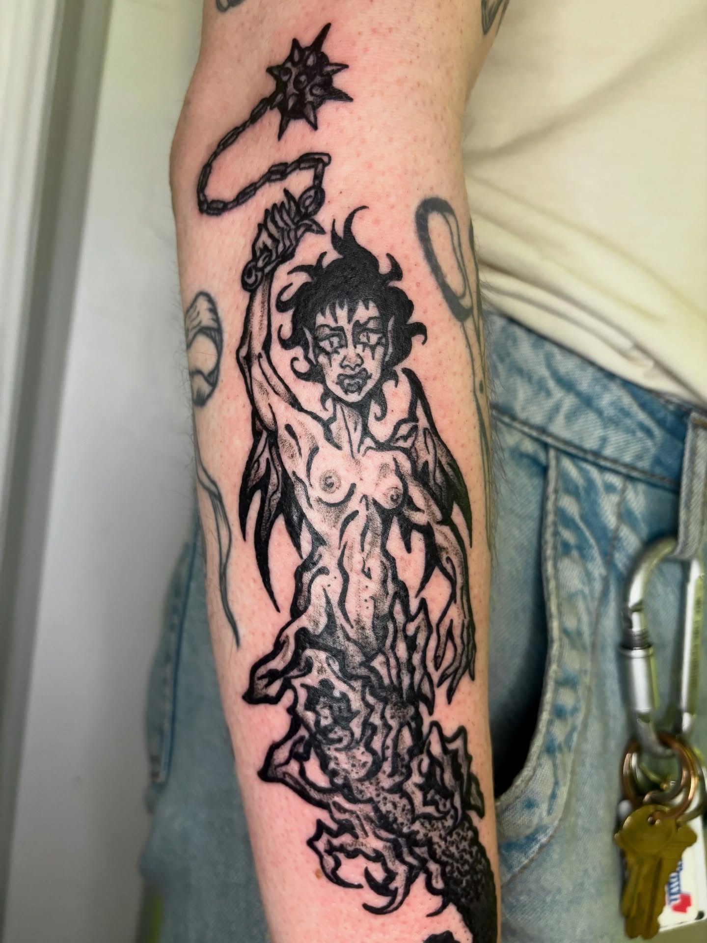 Naked woman with flames black and grey tattoo on the forearm by Grae