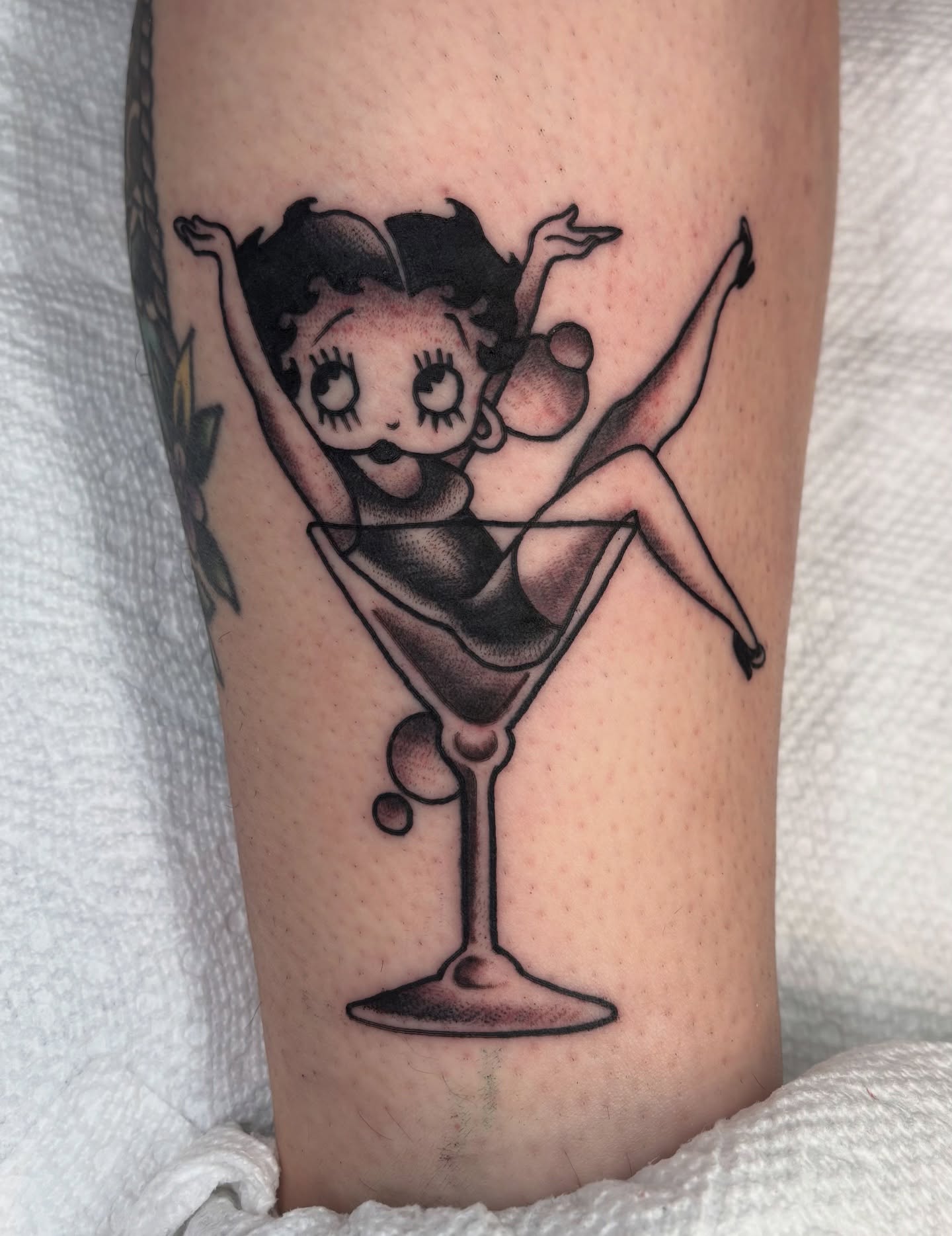 Betty boop in martini glass black and grey tattoo on the forearm by Charlie Dunkel Tattoo