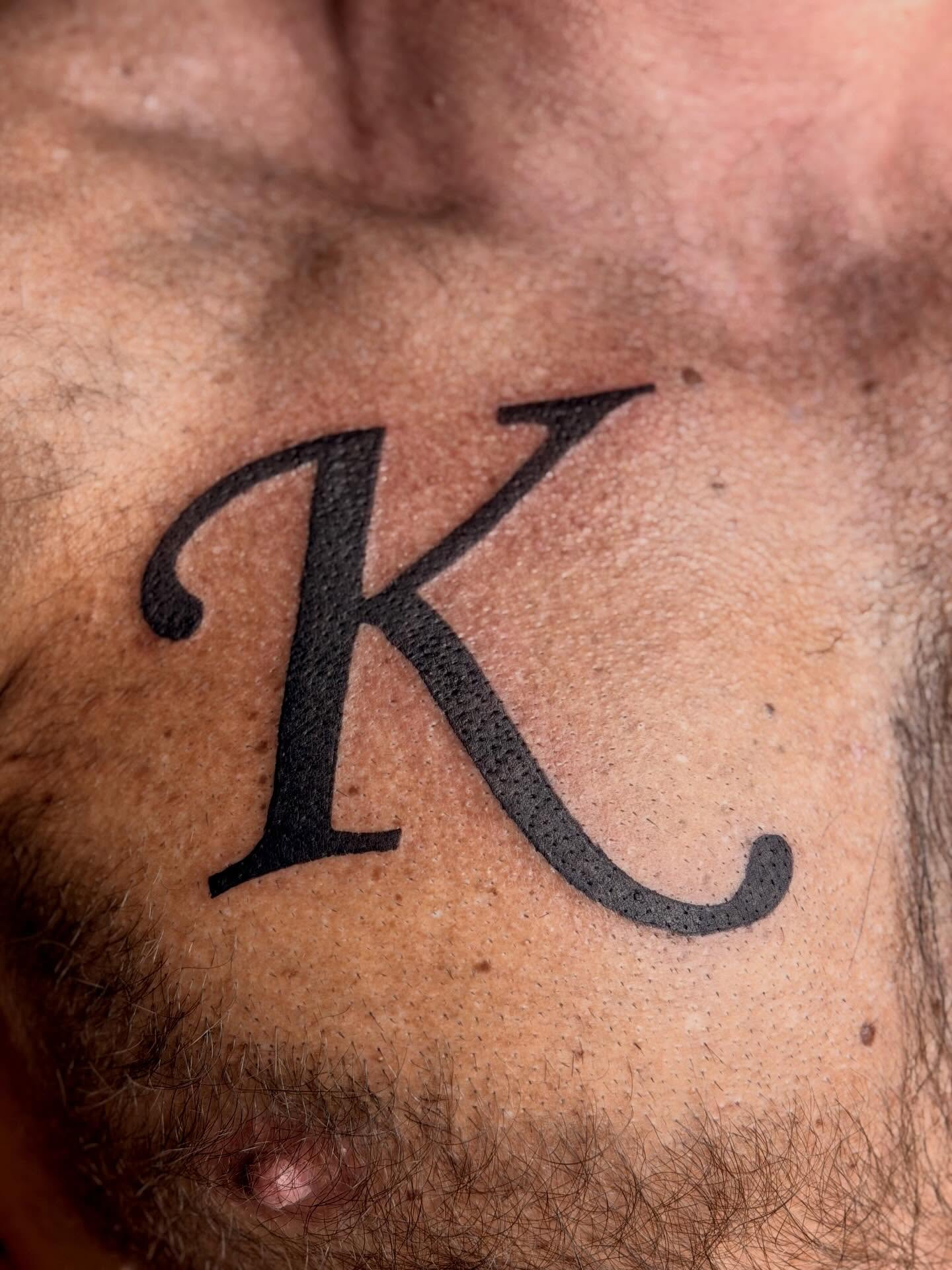 Letter K lettering script tattoo on the chest by ♱ C ♱, Dallas, Texas