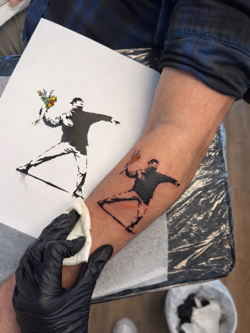 Throwing figure with flowers black and grey tattoo on the forearm by Aristova Anastasia