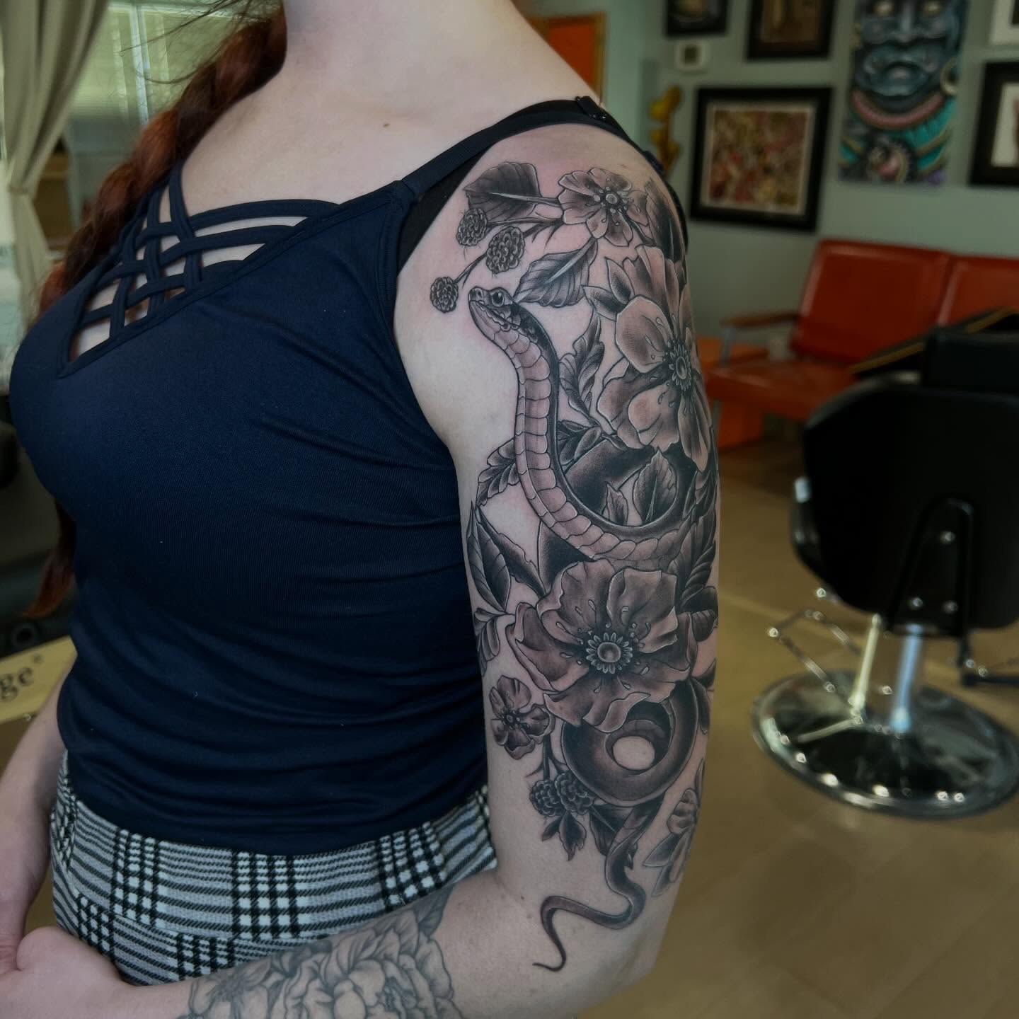 Snake and flowers black and grey tattoo on the upper arm by Jessica Kloos