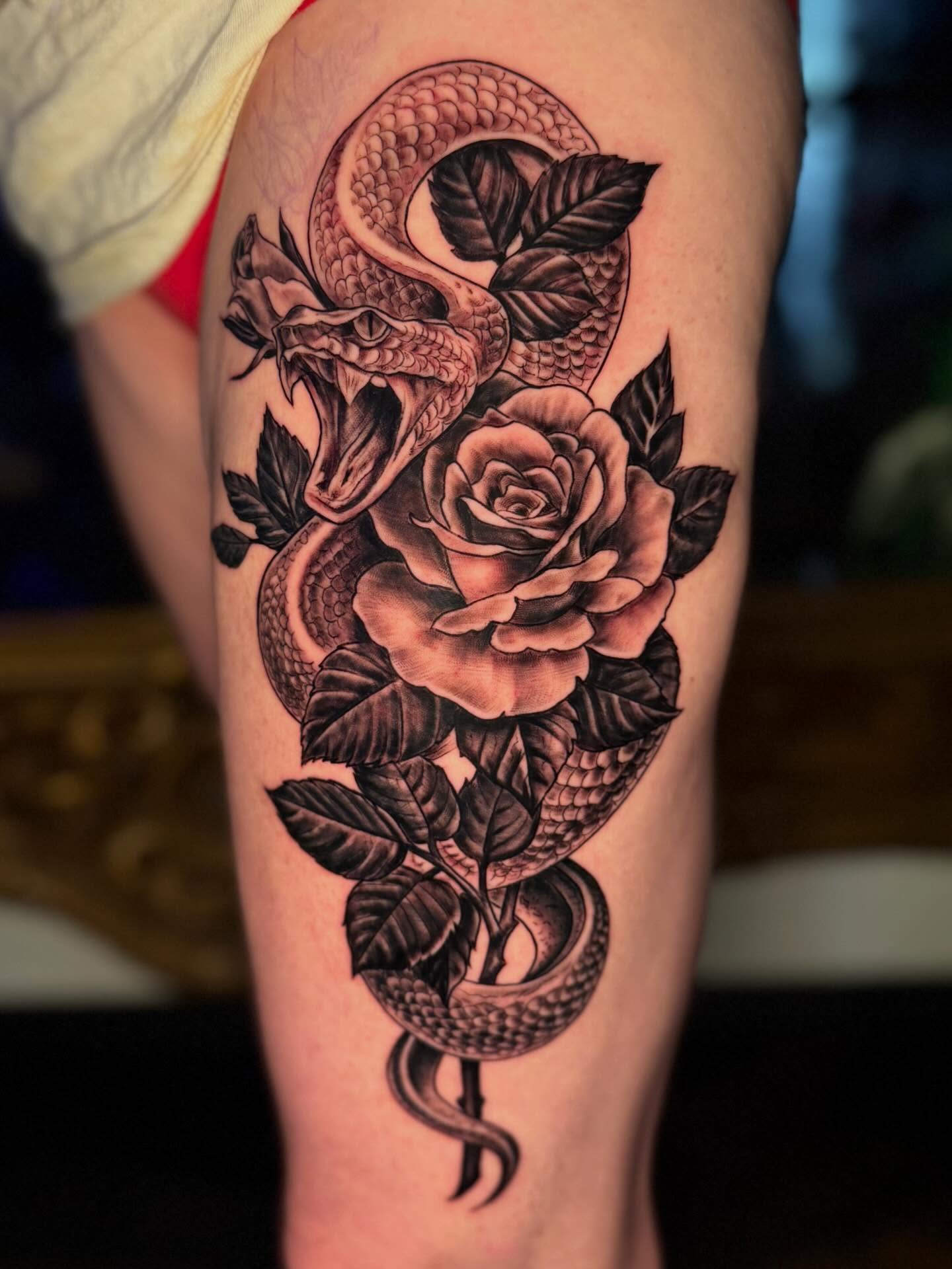 Snake and rose realism tattoo on the thigh by Sergio Ramirez