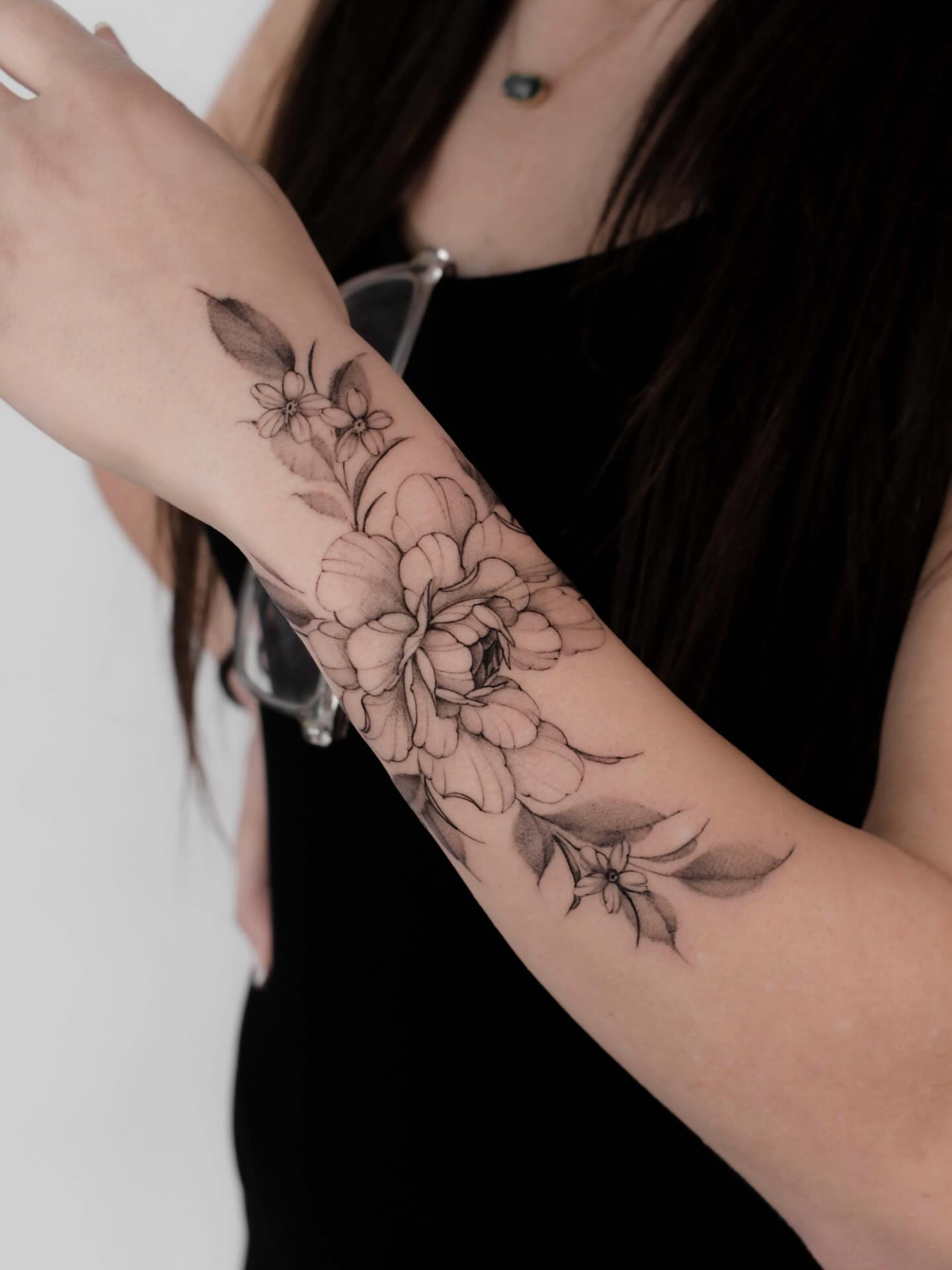 Floral bouquet black and grey tattoo on the forearm by Anastasiia