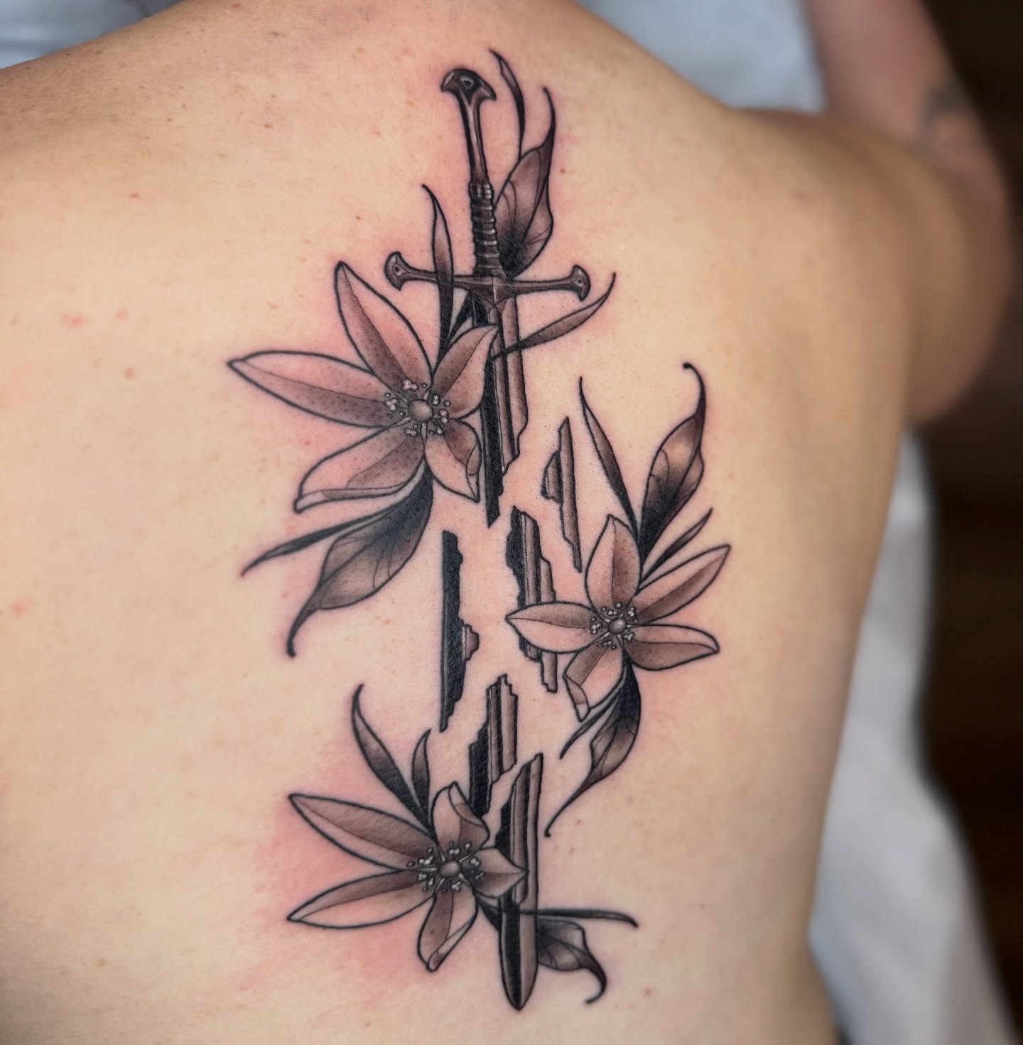 Sword and flowers realism tattoo on the back by Erin Bratzler