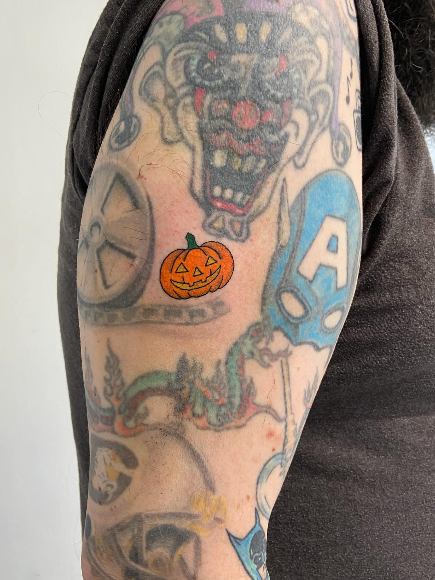 Clown and pumpkin American traditional tattoo on the upper arm by Sophia