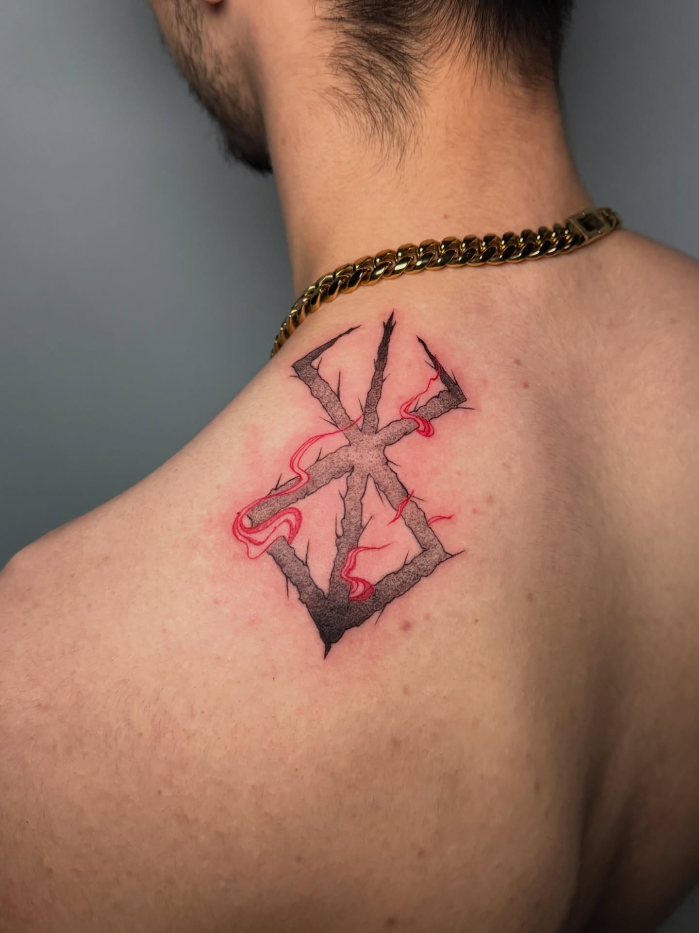 Cross with red accents black and grey tattoo on the shoulder by Jerm Lewis