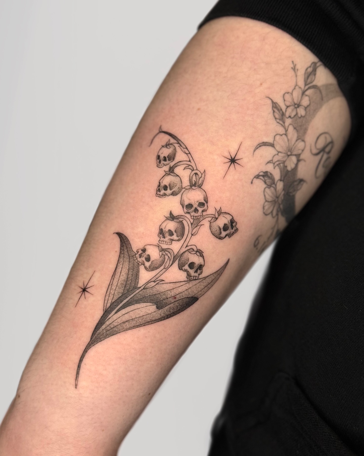 Lily of the valley skulls black and grey tattoo on the forearm by Suzy