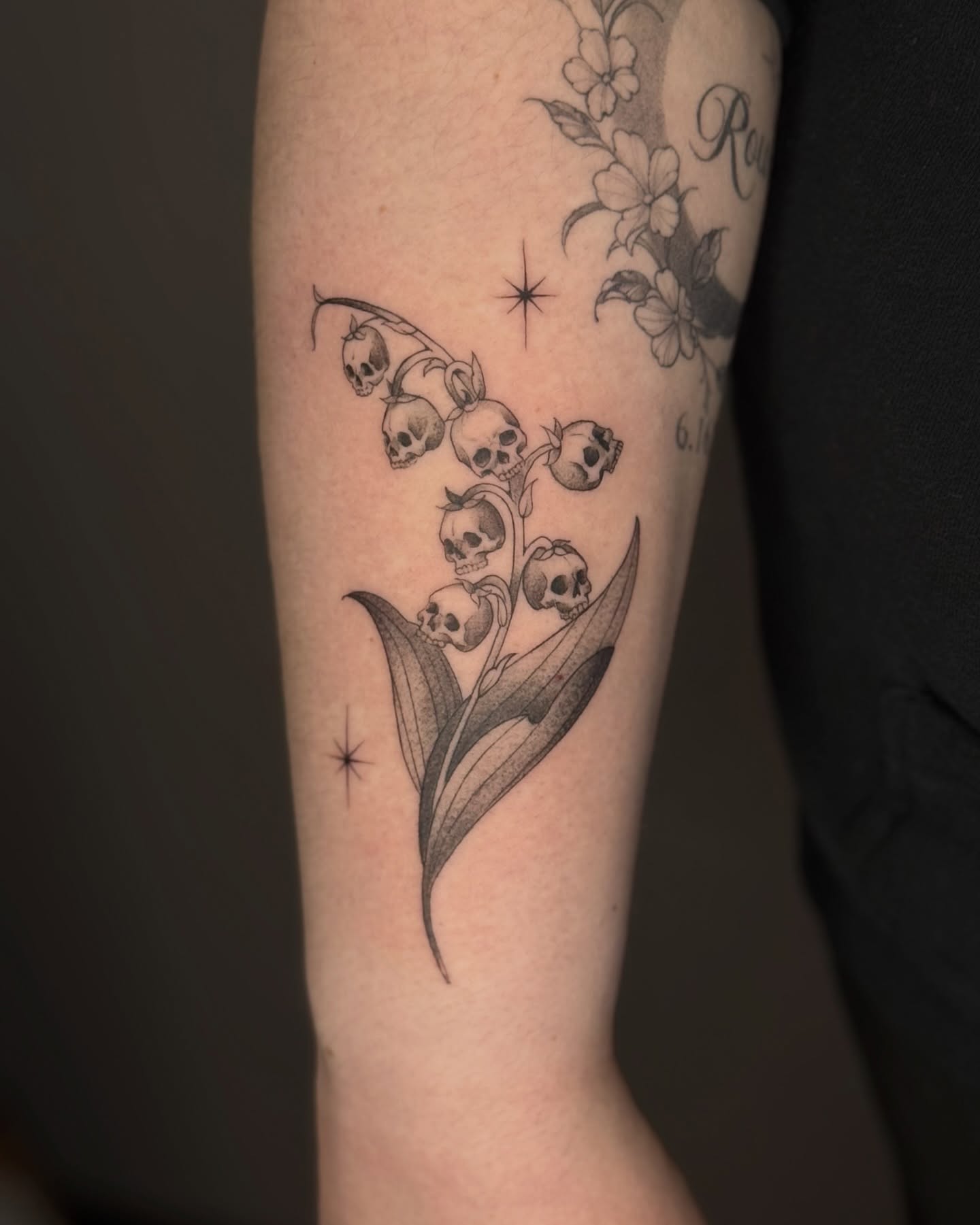 Lily of the valley skulls black and grey tattoo on the forearm by Suzy