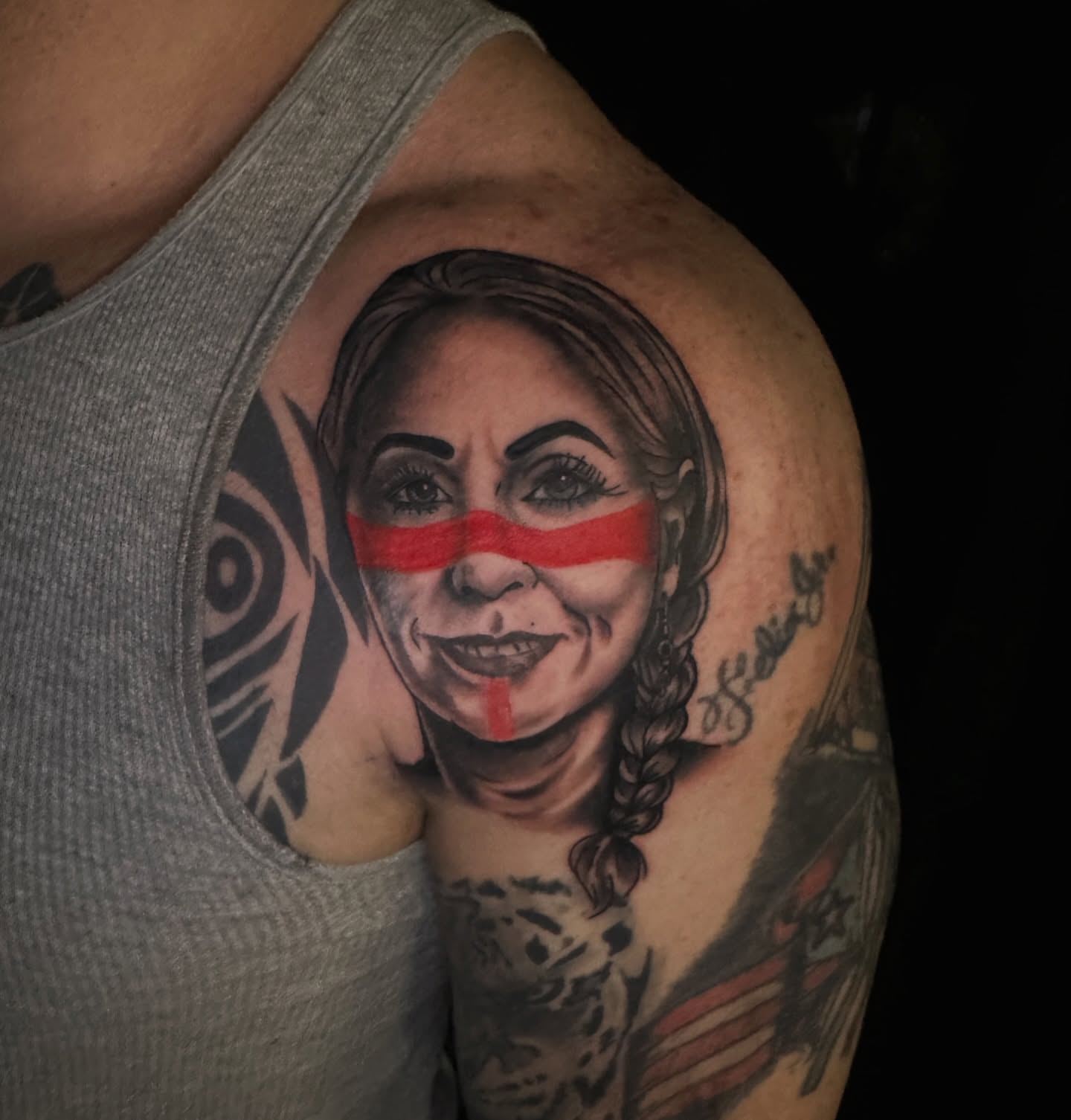 Woman with red stripe realism tattoo on the shoulder by Drew’s Tattoos (NH)