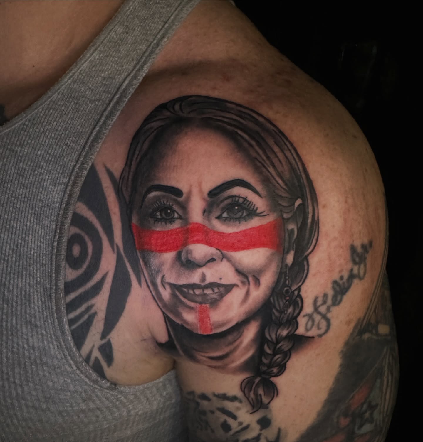 Woman with red stripe realism tattoo on the shoulder by Drew’s Tattoos (NH)