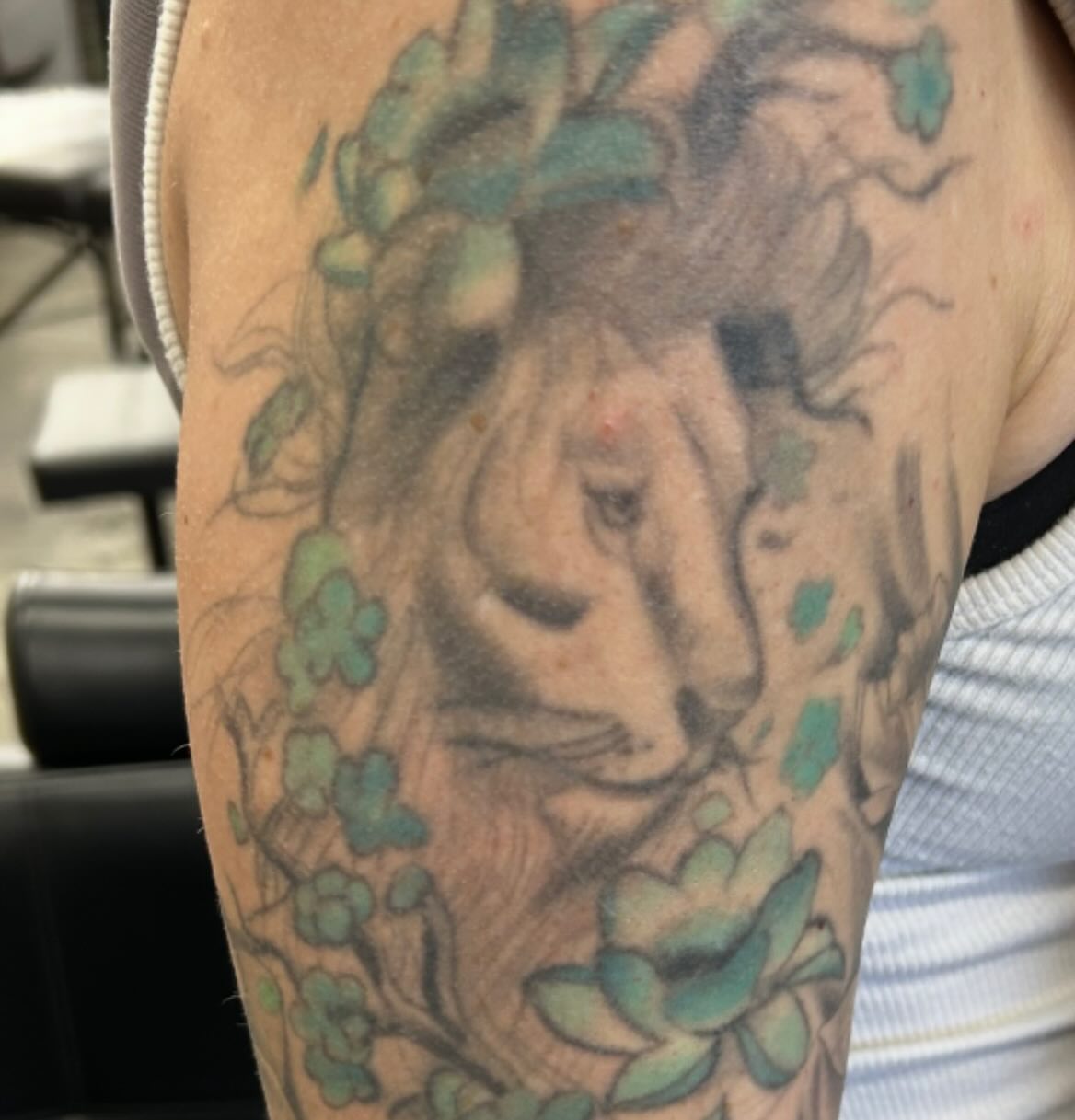 Lion with flowers black and grey tattoo on the forearm by Dylan O'Quin