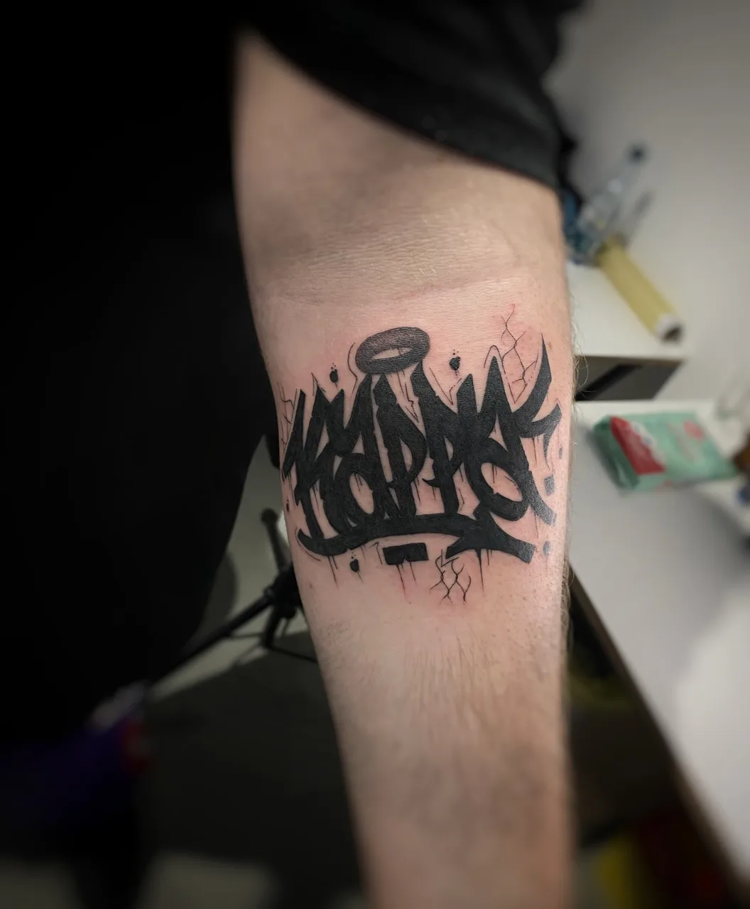 Graffiti-style text black and grey tattoo on the forearm by Blot_Tattoo