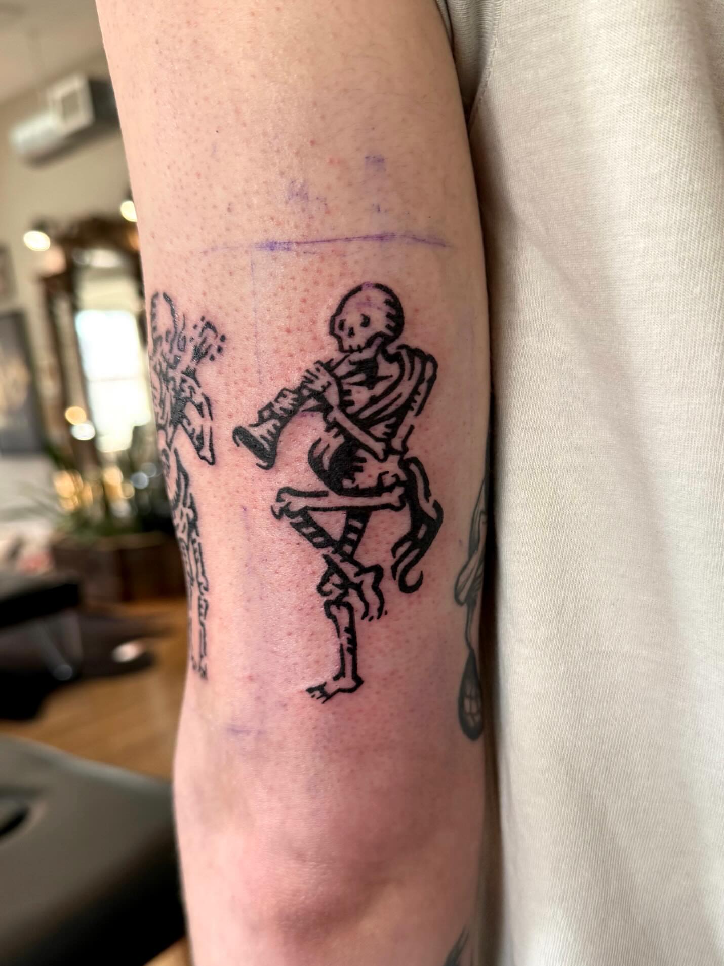 Skeleton playing bagpipes black and grey tattoo on the forearm by M