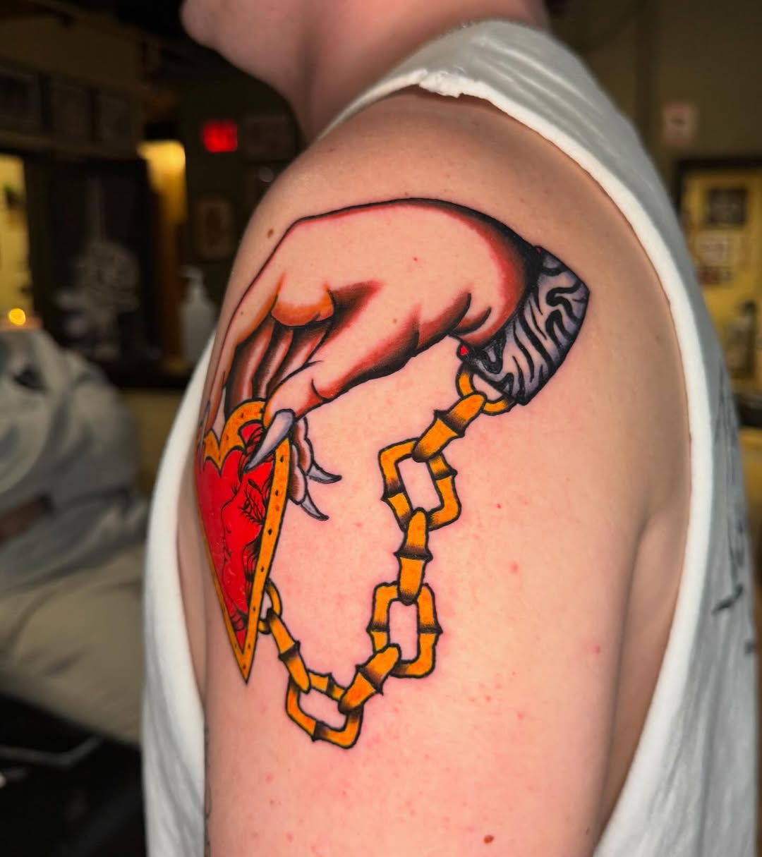 Hand holding a heart locket American traditional tattoo on the shoulder by @michaelryan_tattoo