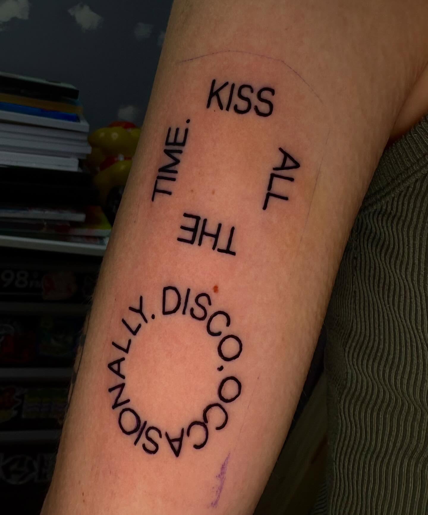 KISS ALL THE TIME OCCASIONALLY DISCO lettering script tattoo on the forearm by Jenna Clayton