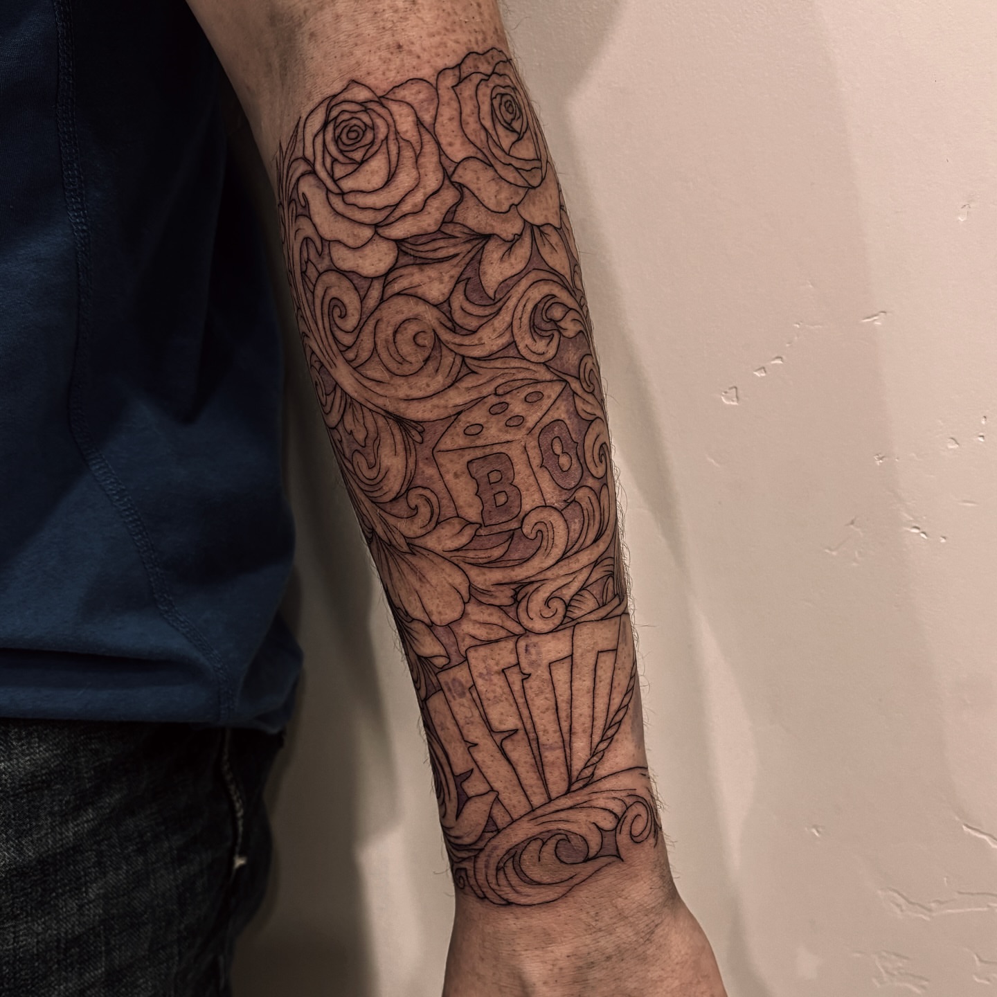 Roses and dice black and grey tattoo on the forearm by Tayler, Tooele, Utah