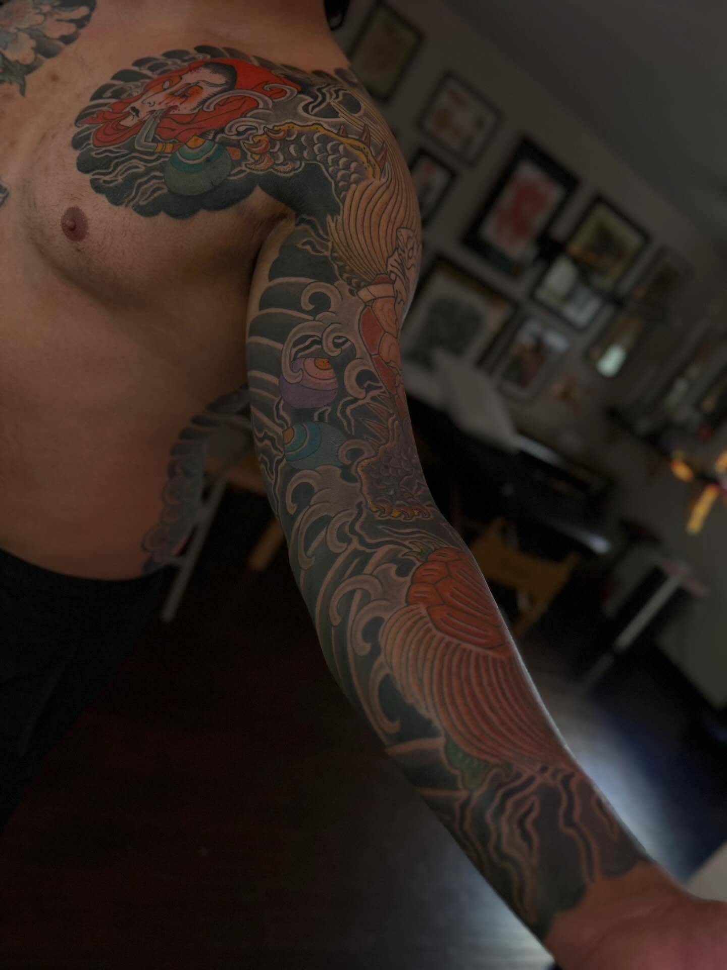 Dragon and waves japanese irezumi tattoo on the upper arm by Kenny Waizumi ๐