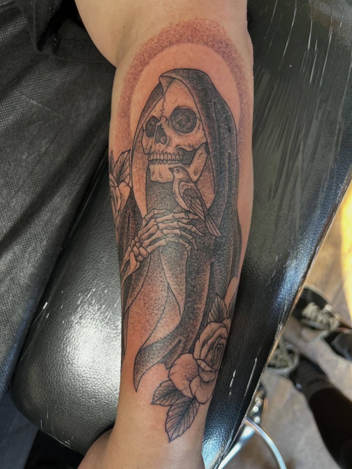 Grim reaper with bird and roses realism tattoo on the forearm by Jaime Gaiti