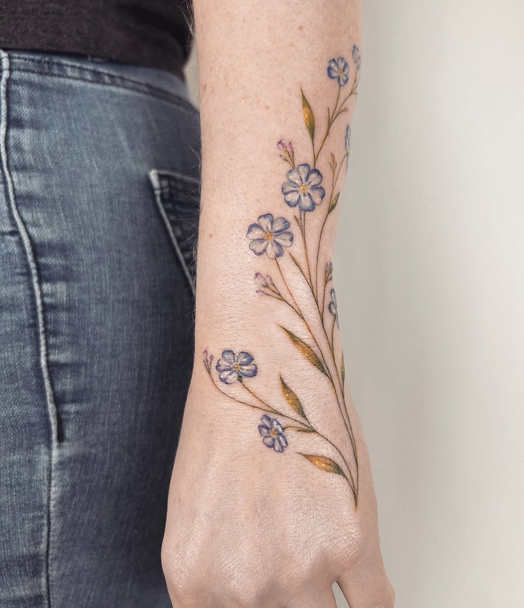 Forget-me-not flowers watercolor tattoo on the forearm by Helly March