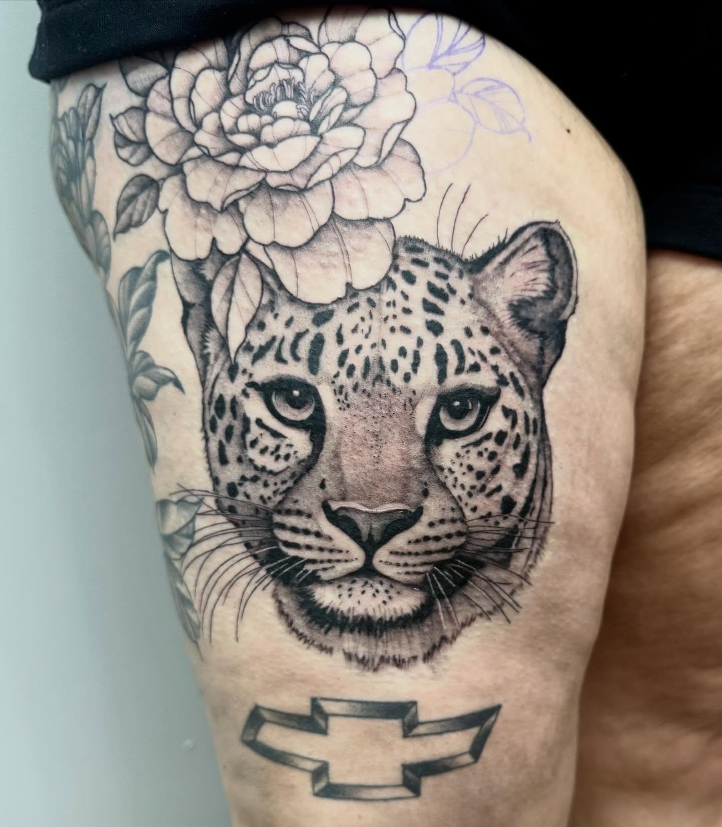 Leopard and flower realism tattoo on the thigh by Emmy