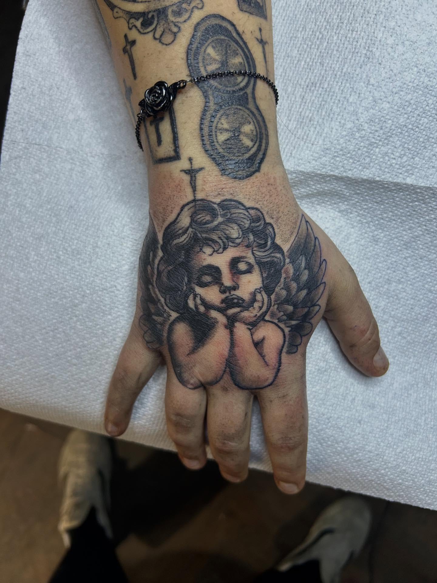 Cherub black and grey tattoo on the hand by Randy Bray