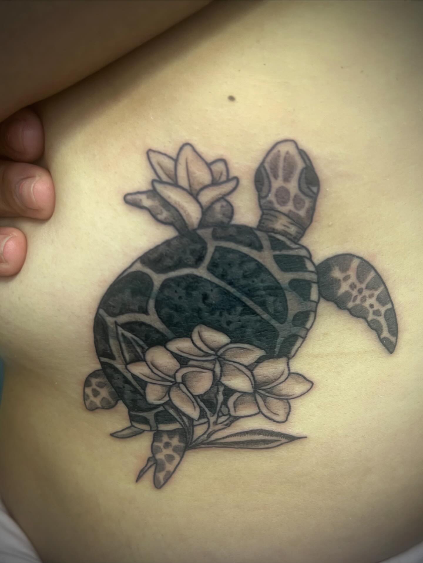 Sea turtle with flowers black and grey tattoo on the ribs by Natalie Phillips, Oakland, California