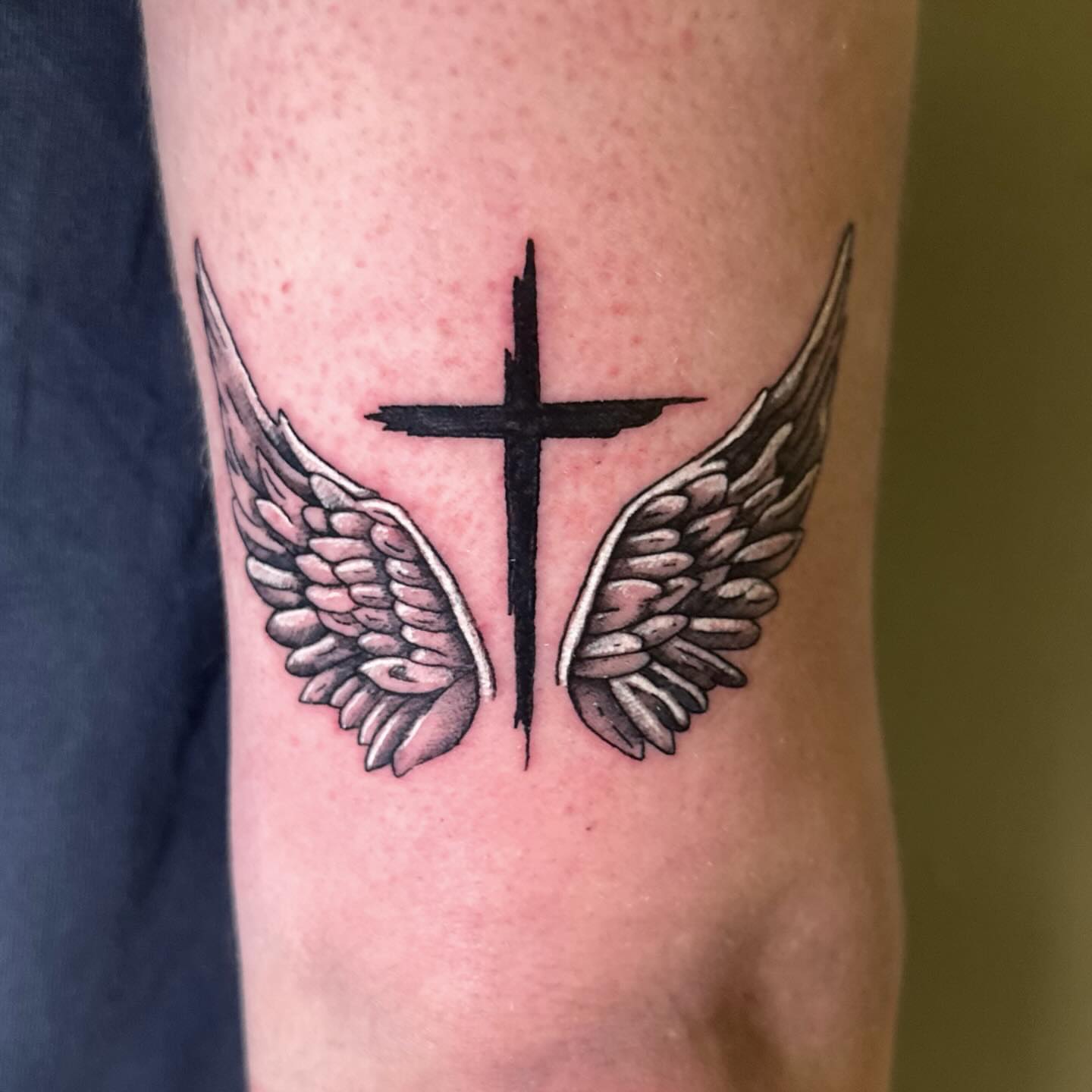 Cross with wings black and grey tattoo on the forearm by Sam, Mount Laurel, New Jersey