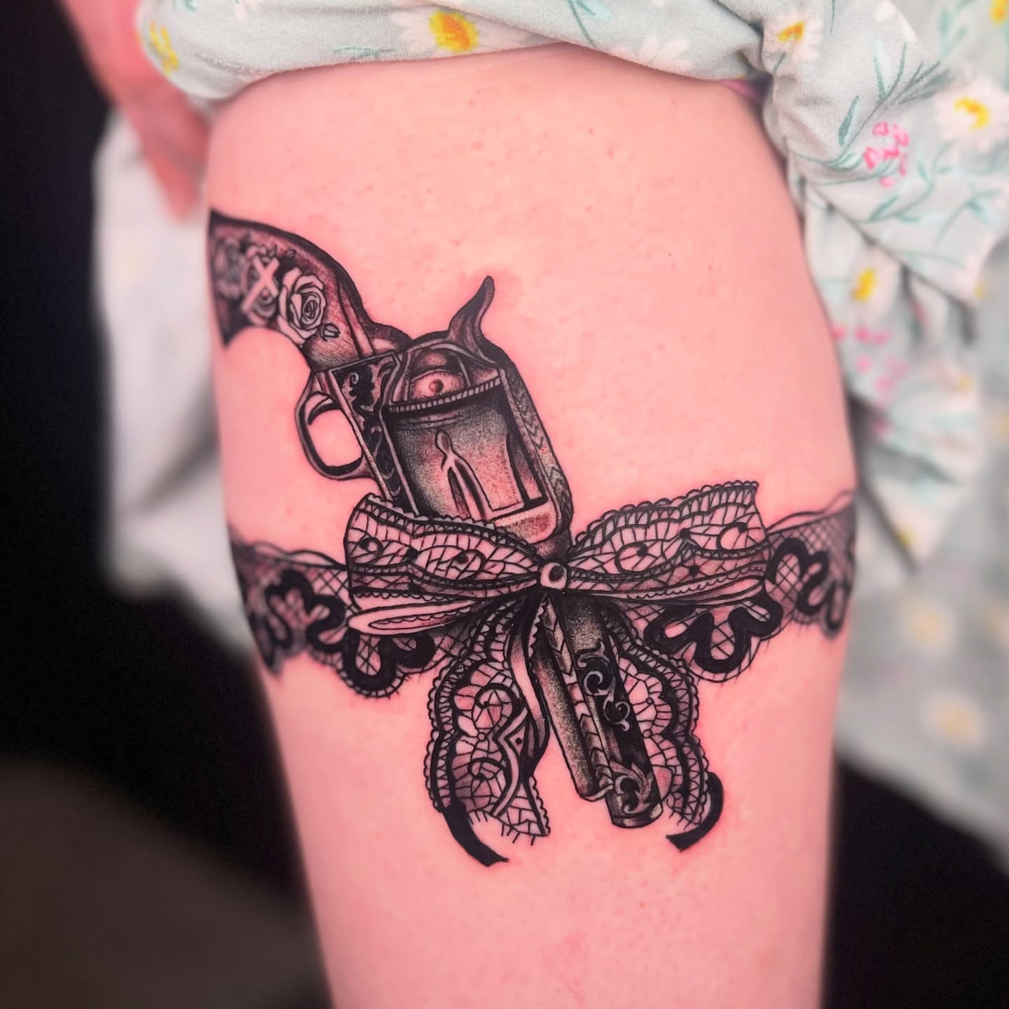 Gun and lace bow geometric tattoo on the thigh by Tevin Thomas
