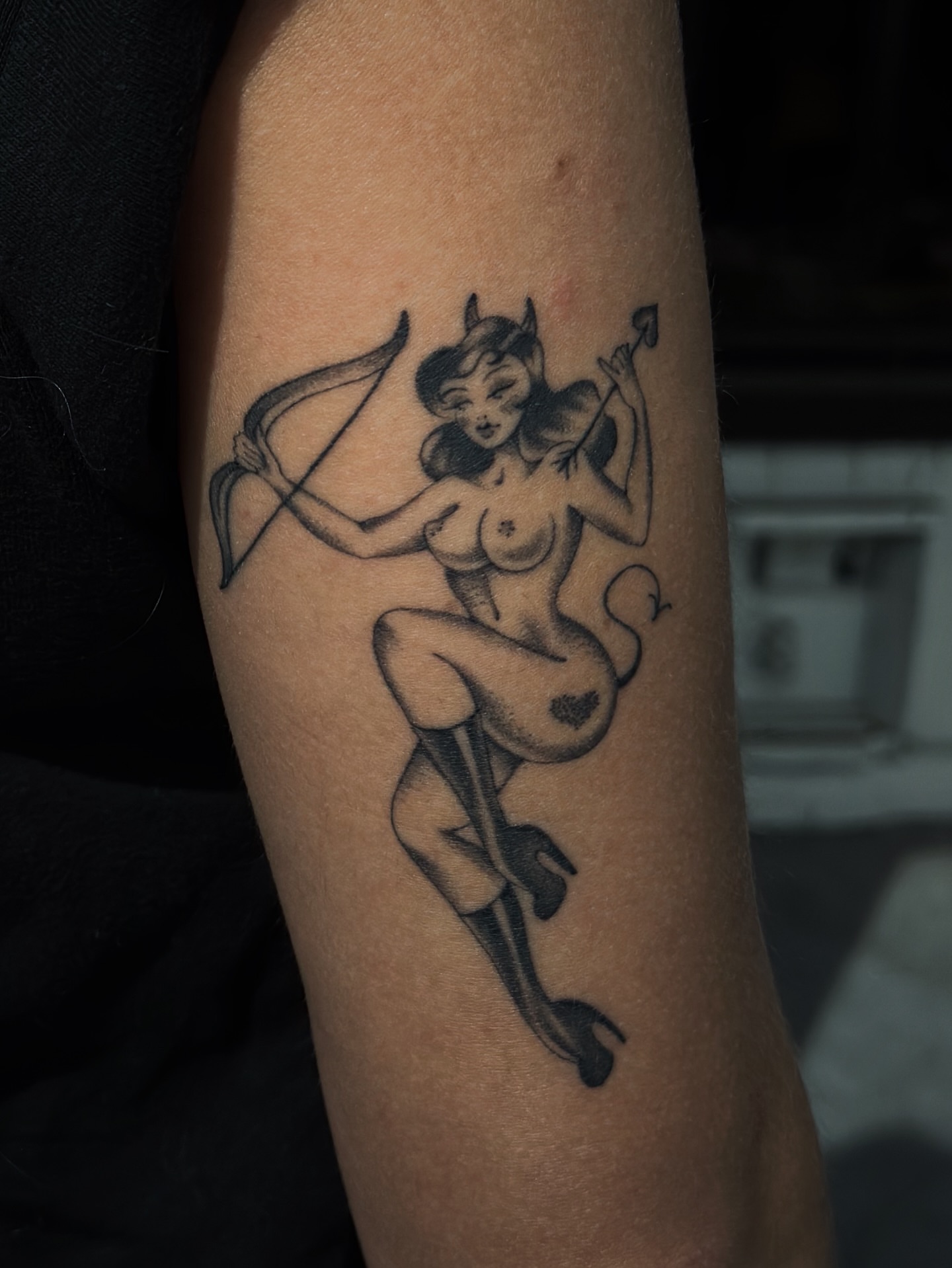 Devil pin-up girl black and grey tattoo on the forearm by Lauryn Jenesis