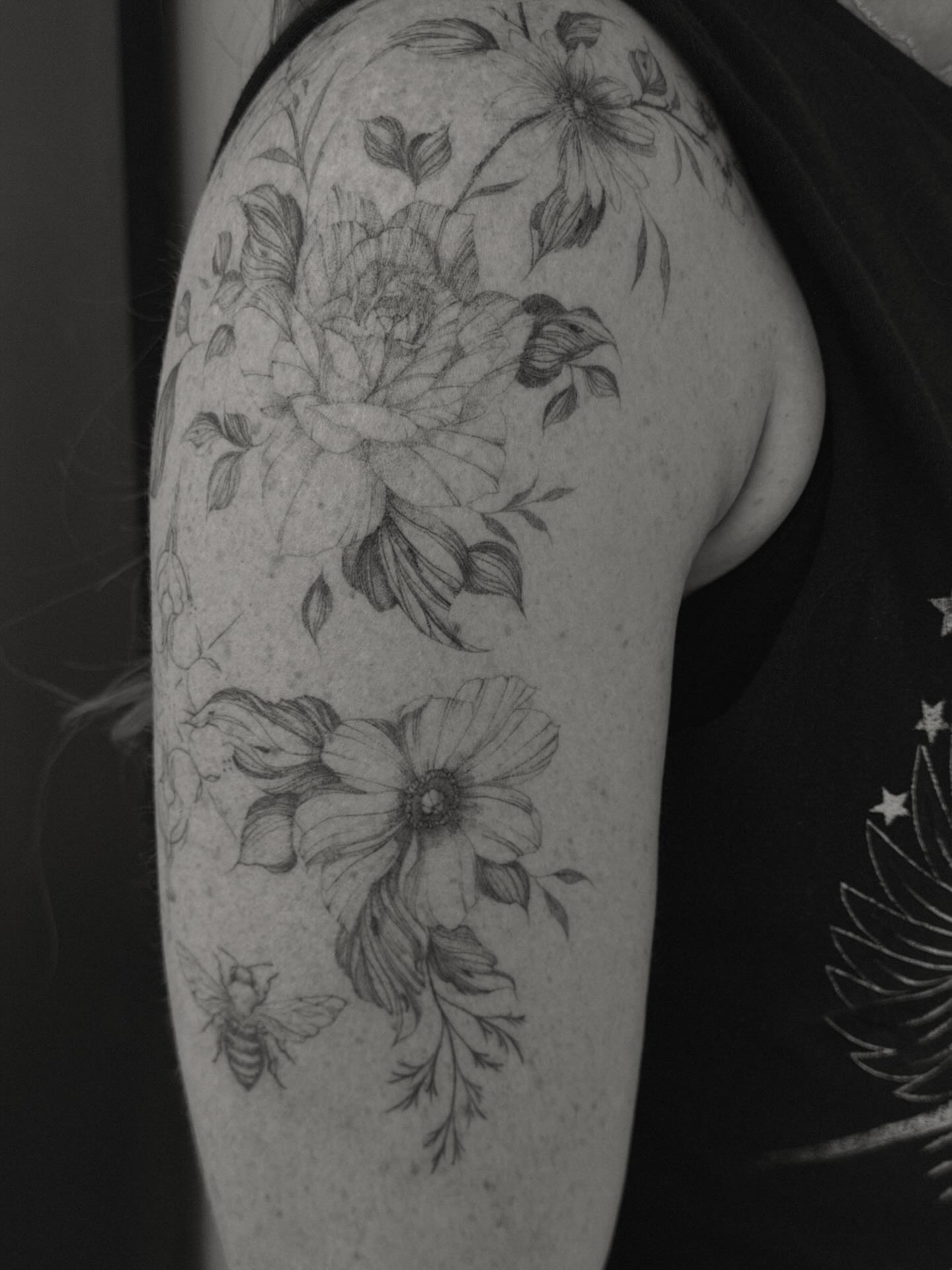 Floral arrangement black and grey tattoo on the upper arm by Hannah Matthews