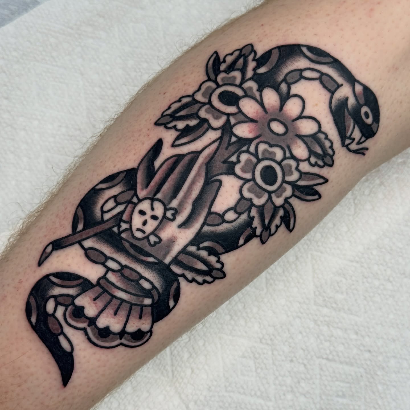 Mask and flowers American traditional tattoo on the forearm by Rafael Torres, San Francisco, California