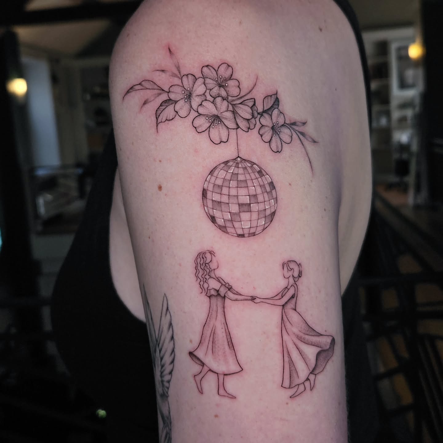 Dancers with disco ball realism tattoo on the upper arm by Courtlyn Bliss