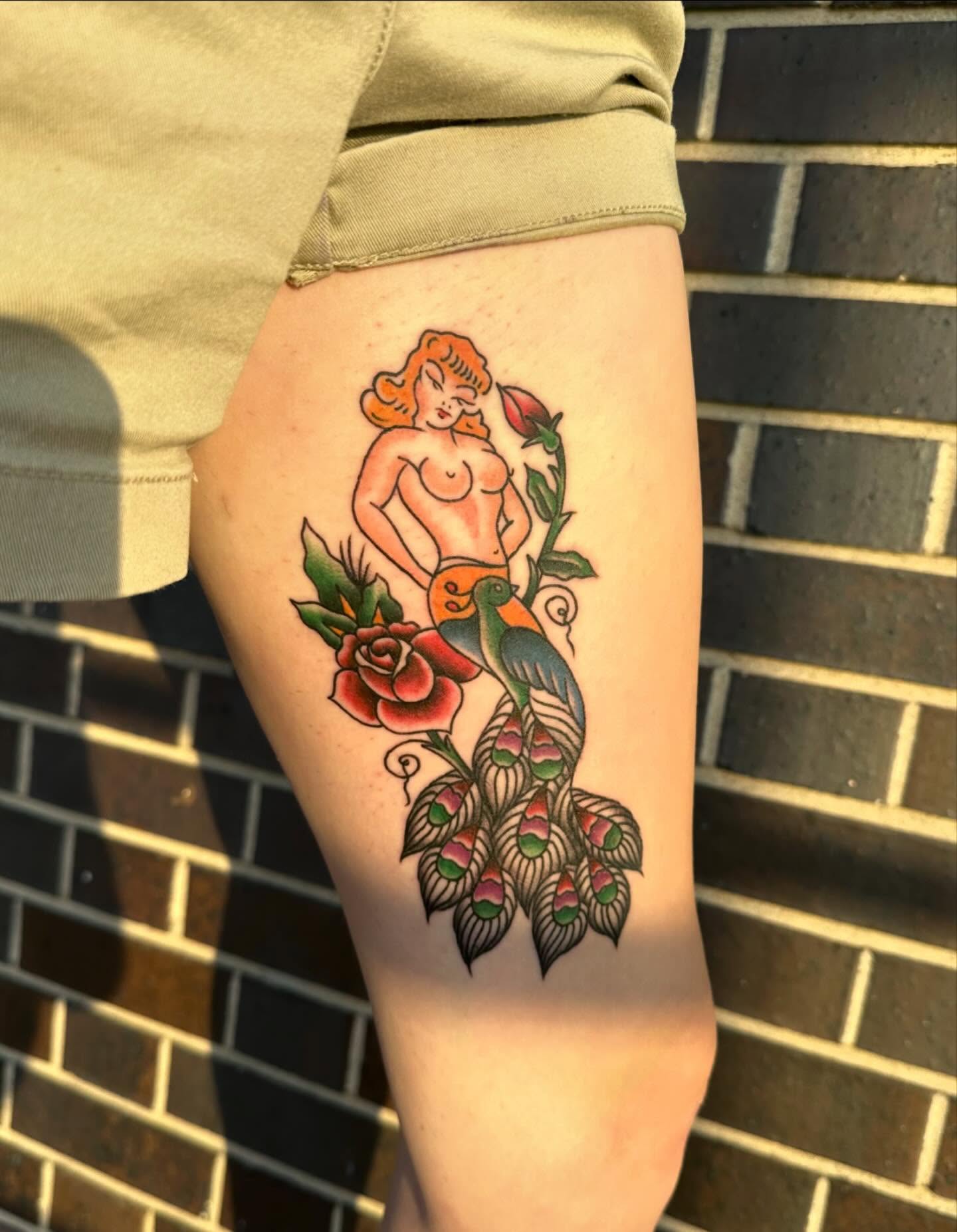 Woman with bird and roses American traditional tattoo on the thigh by Kerri Colello Sittenauer
