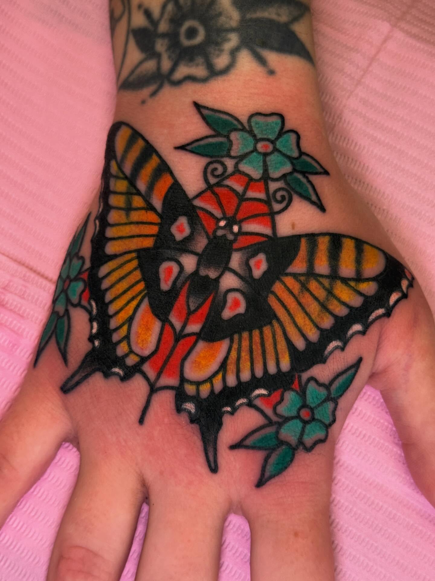 Butterfly and flowers American traditional tattoo on the hand by Cassie O'Neal DeBord