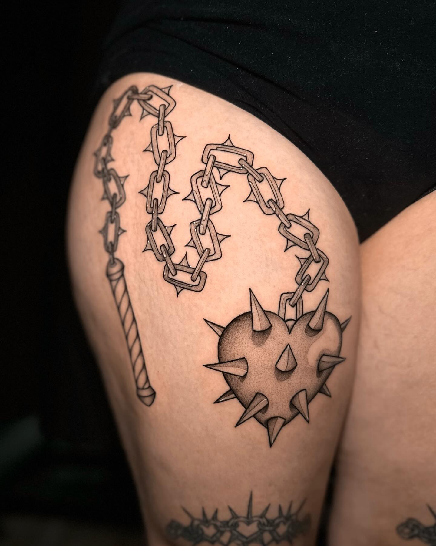Spiked heart with chains black and grey tattoo on the thigh by Frida Tattooista