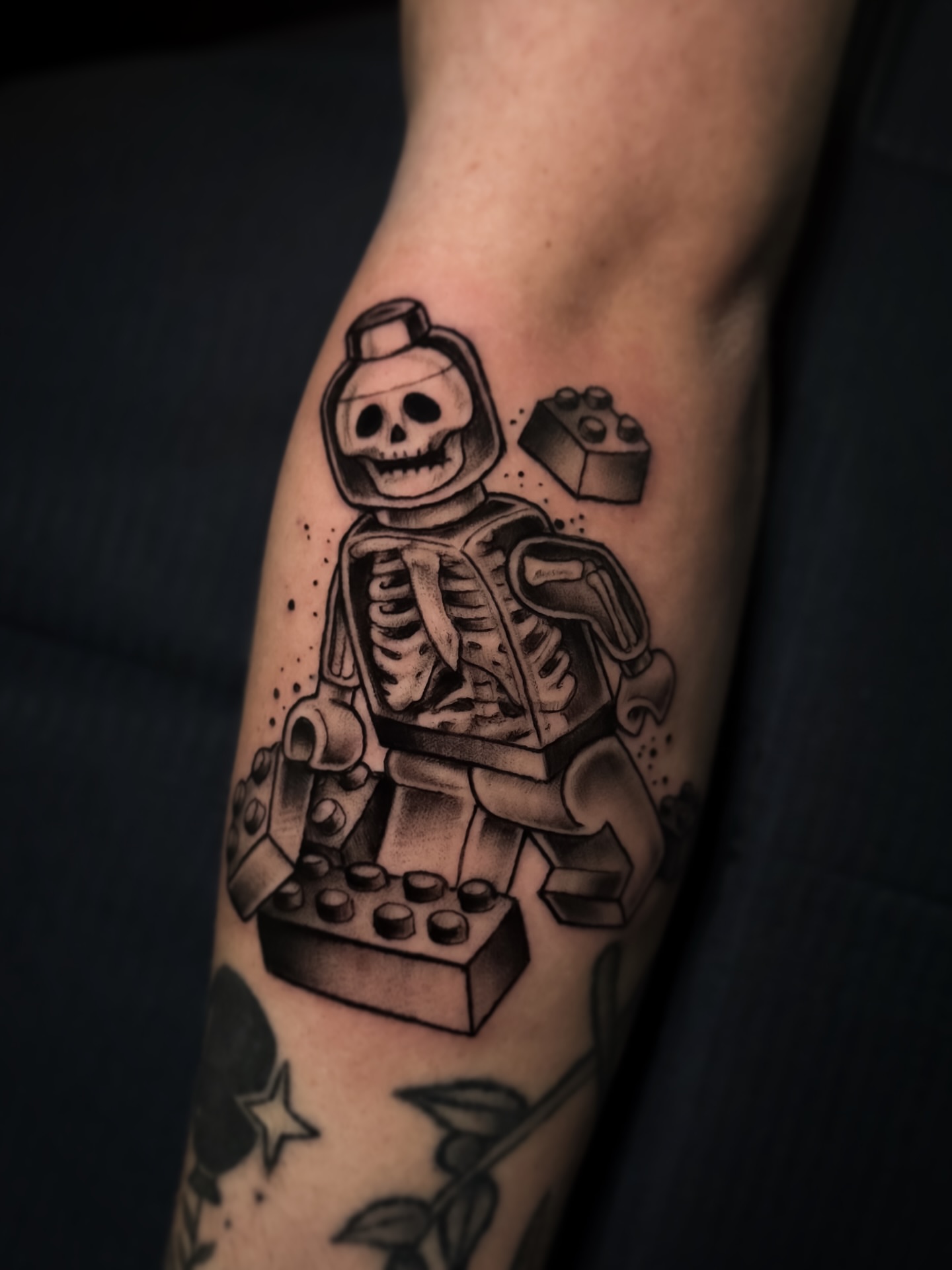 LEGO skeleton black and grey tattoo on the forearm by Cristen Aro