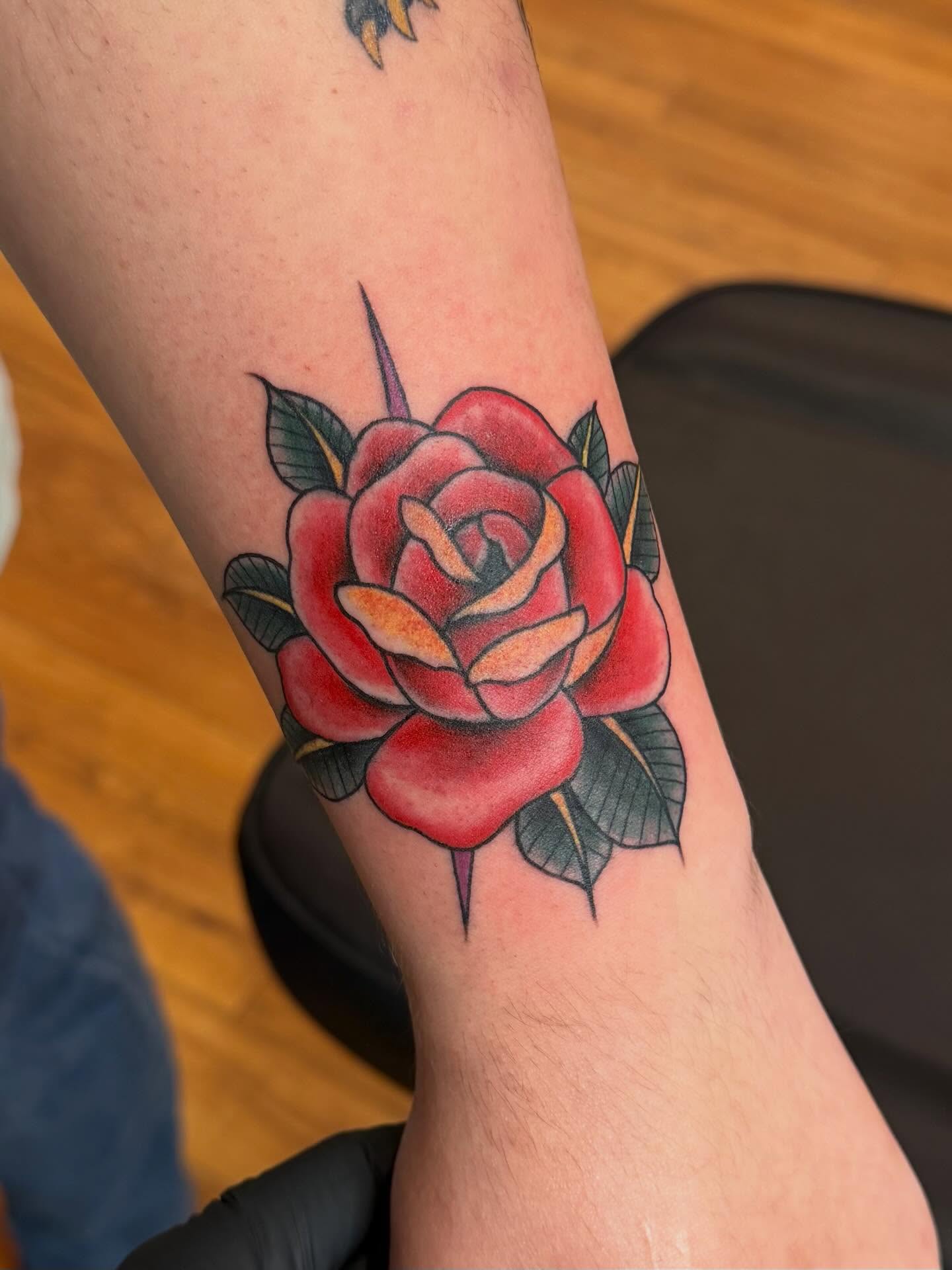 Red rose American traditional tattoo on the forearm by Madilynn Klassen