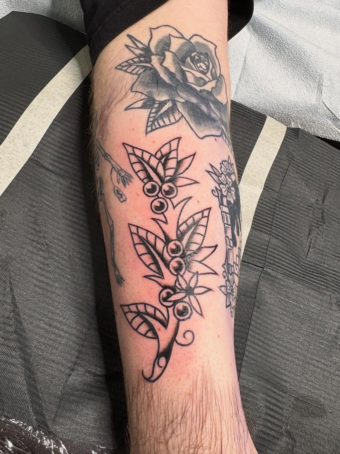 Rose and floral arrangement black and grey tattoo on the forearm by ellie