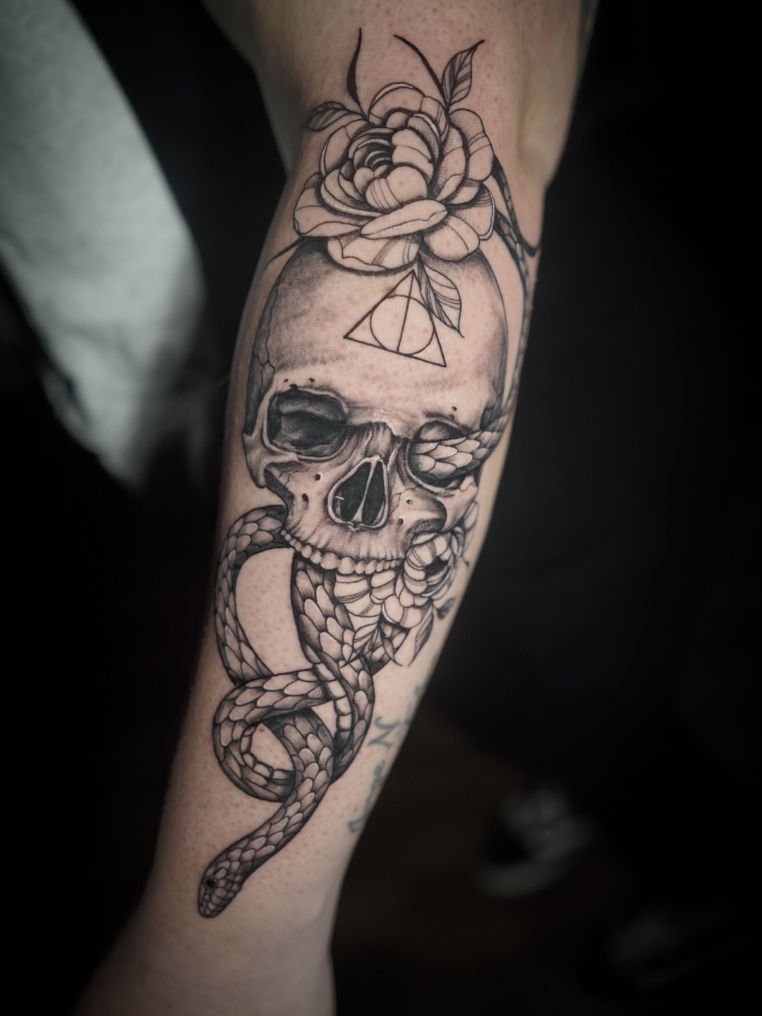 Skull with snake and rose realism tattoo on the forearm by Niko Hosk Cataldo