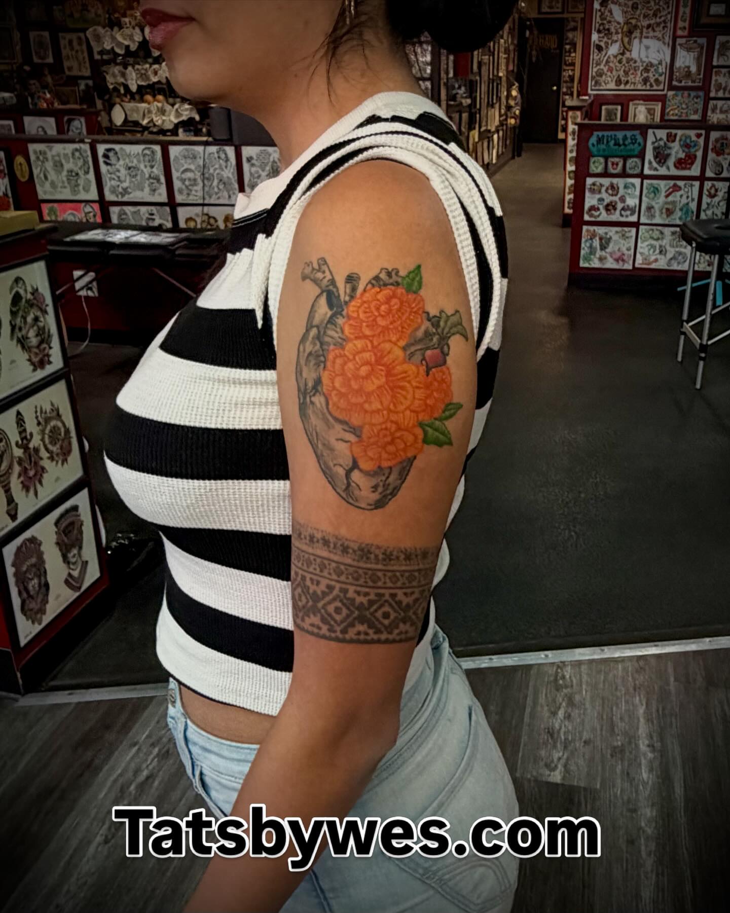 Orange flower in heart American traditional tattoo on the upper arm by 𝐖𝐄𝐒