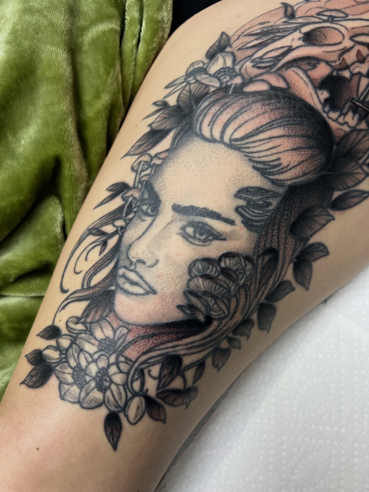 Woman's face with floral elements dotwork tattoo on the thigh by Nathan Garcia