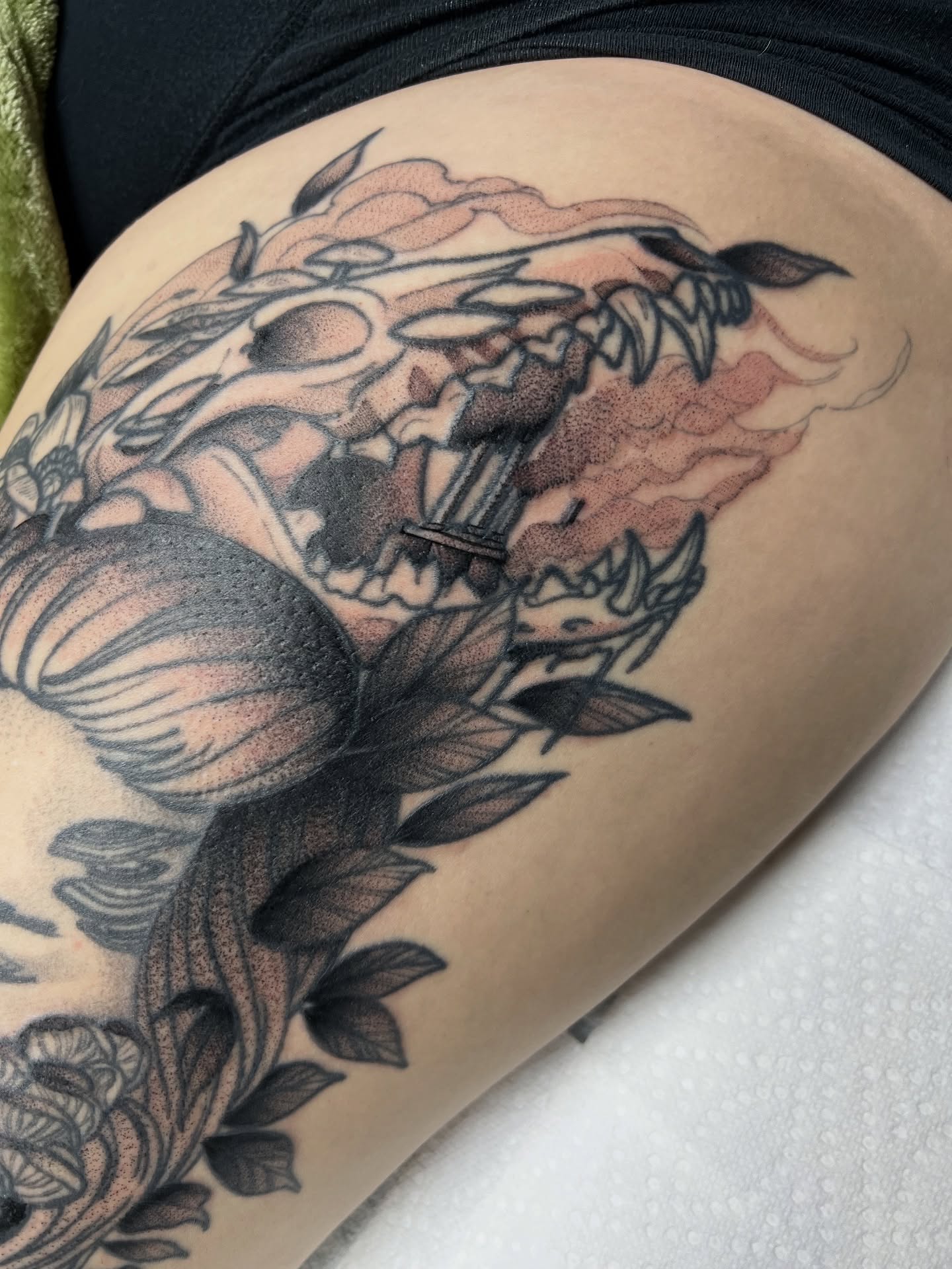 Skull and leaves black and grey tattoo on the thigh by Nathan Garcia