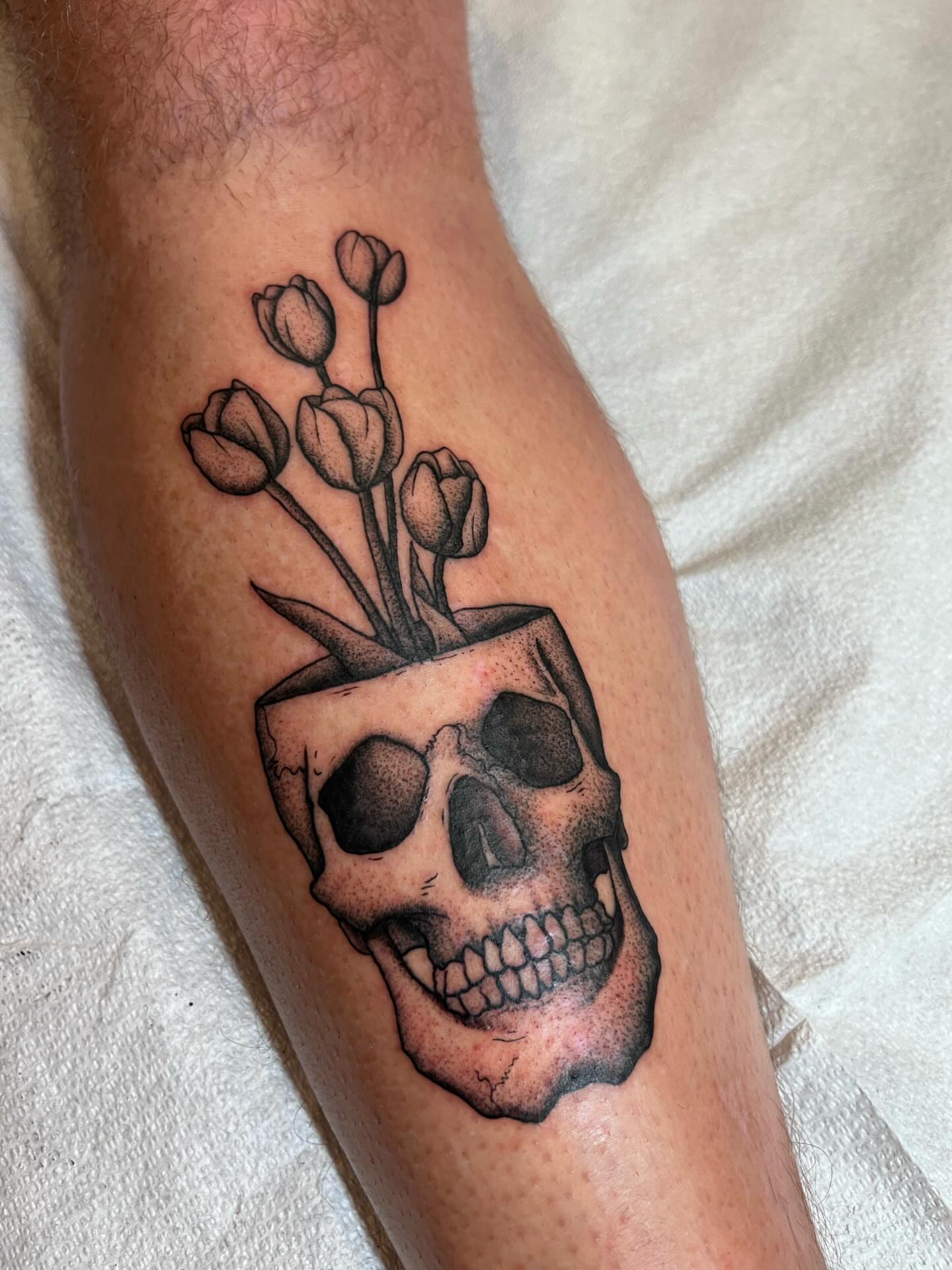 Skull with flowers black and grey tattoo on the forearm by Jackson Kirchhoff