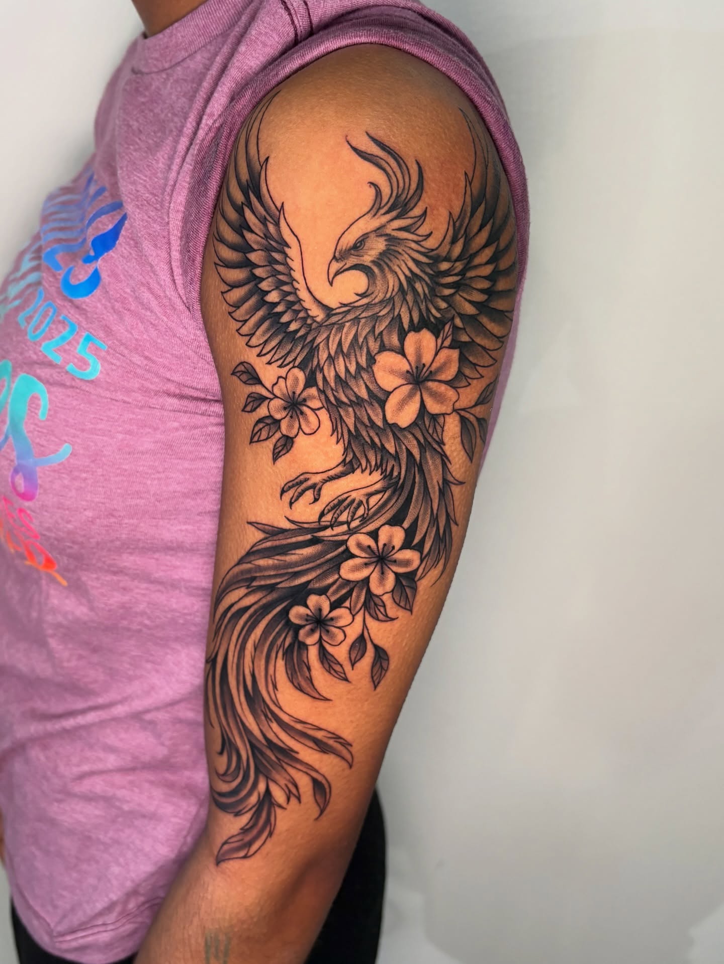 Phoenix and flowers black and grey tattoo on the upper arm by Osiel Rodriguez